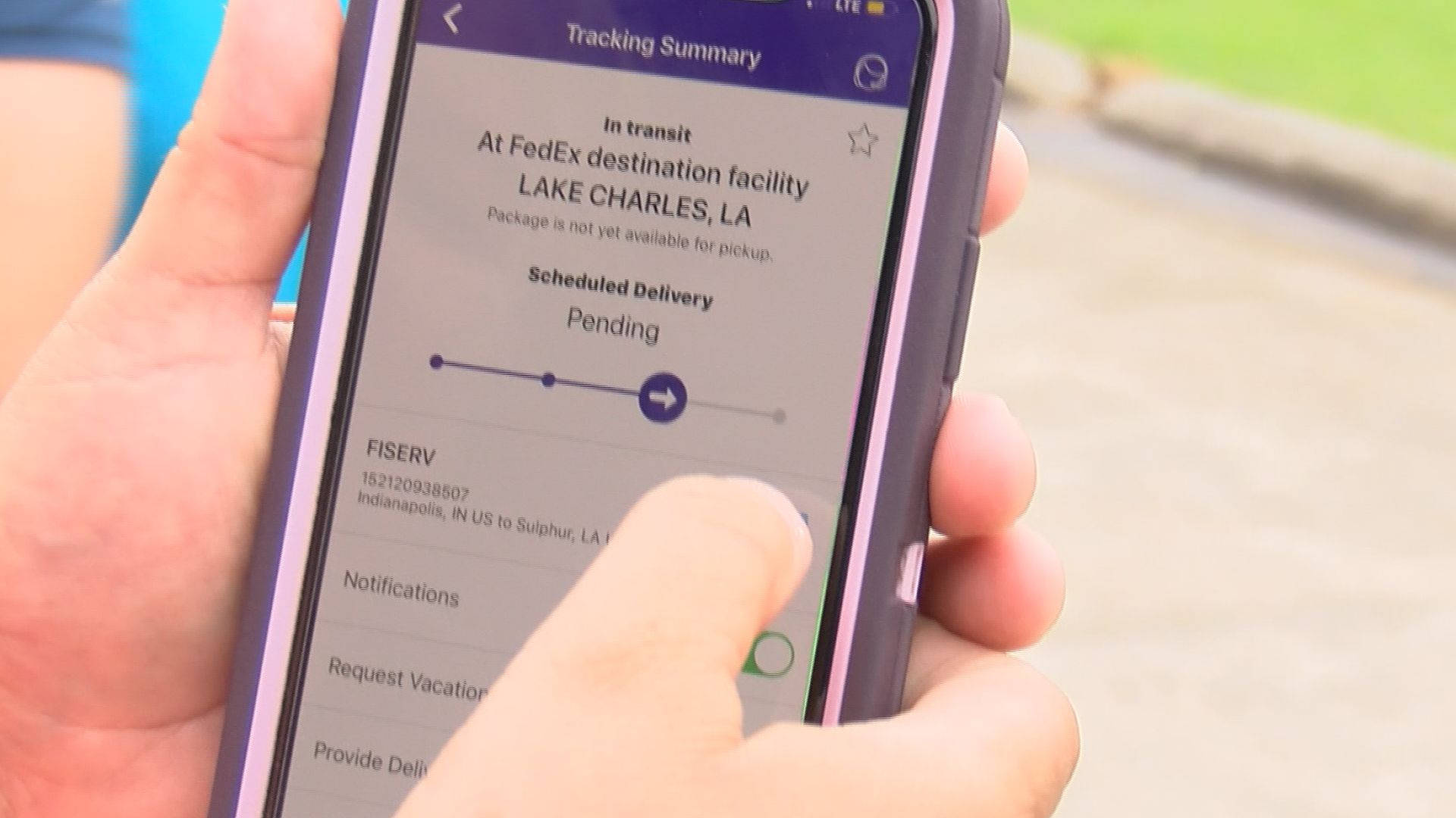 手拿著電話顯示FedEx包裹追蹤到路易斯安那州查爾斯湖