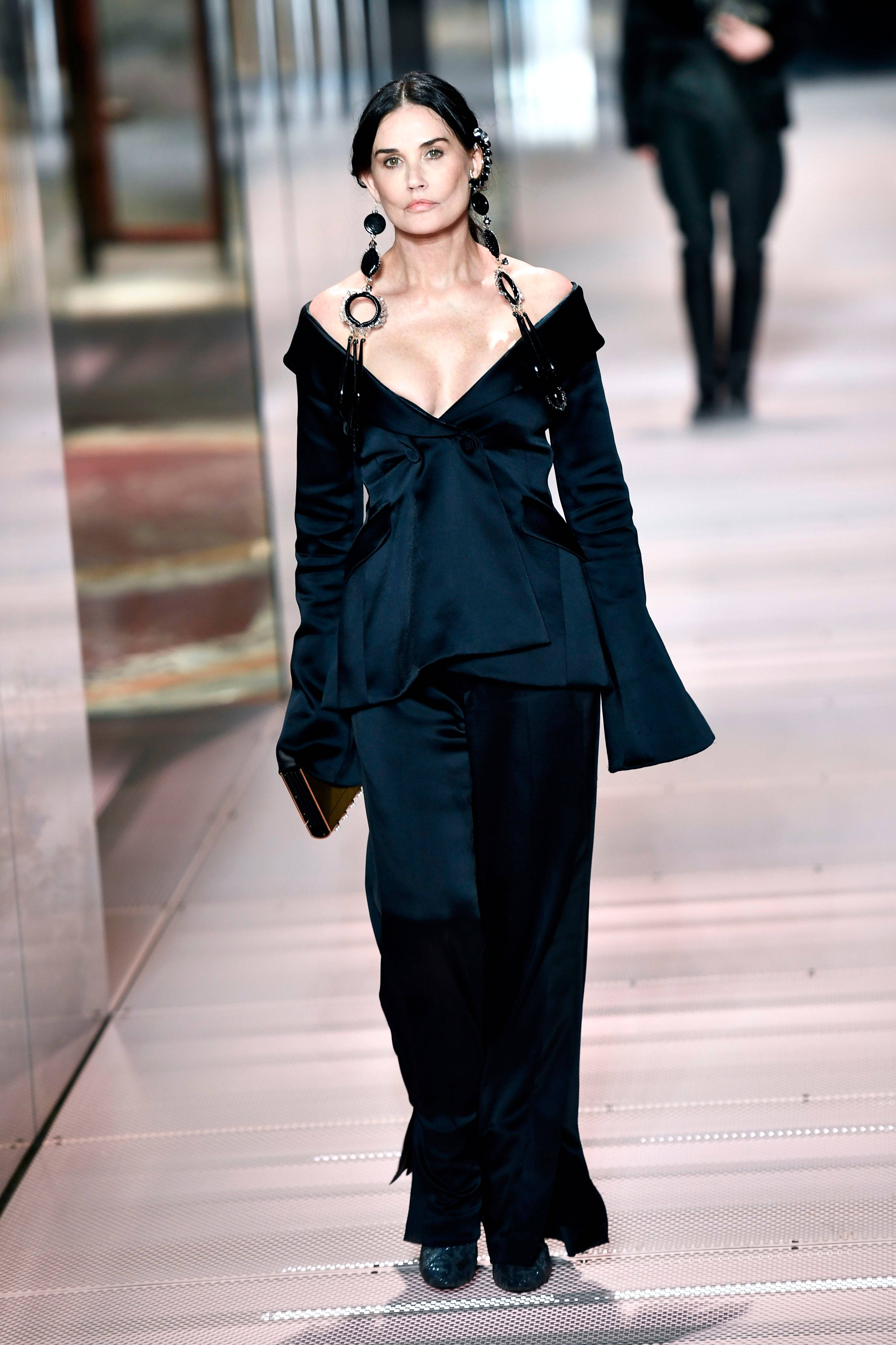 Fendi 模特穿禮服 壁紙 — 模特兒自信地走在天橋上，身穿優雅的黑色露肩緞面服裝，配以戲劇性的鐘形袖和搶眼耳環。