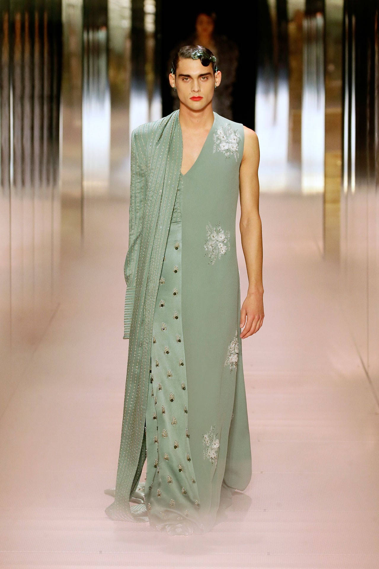 Fendi 綠色長禮服 壁紙 — 一位模特兒穿著優雅的鼠尾草綠色無袖長裙，帶有花卉刺繡和相配的垂墜外套，走在天橋上。