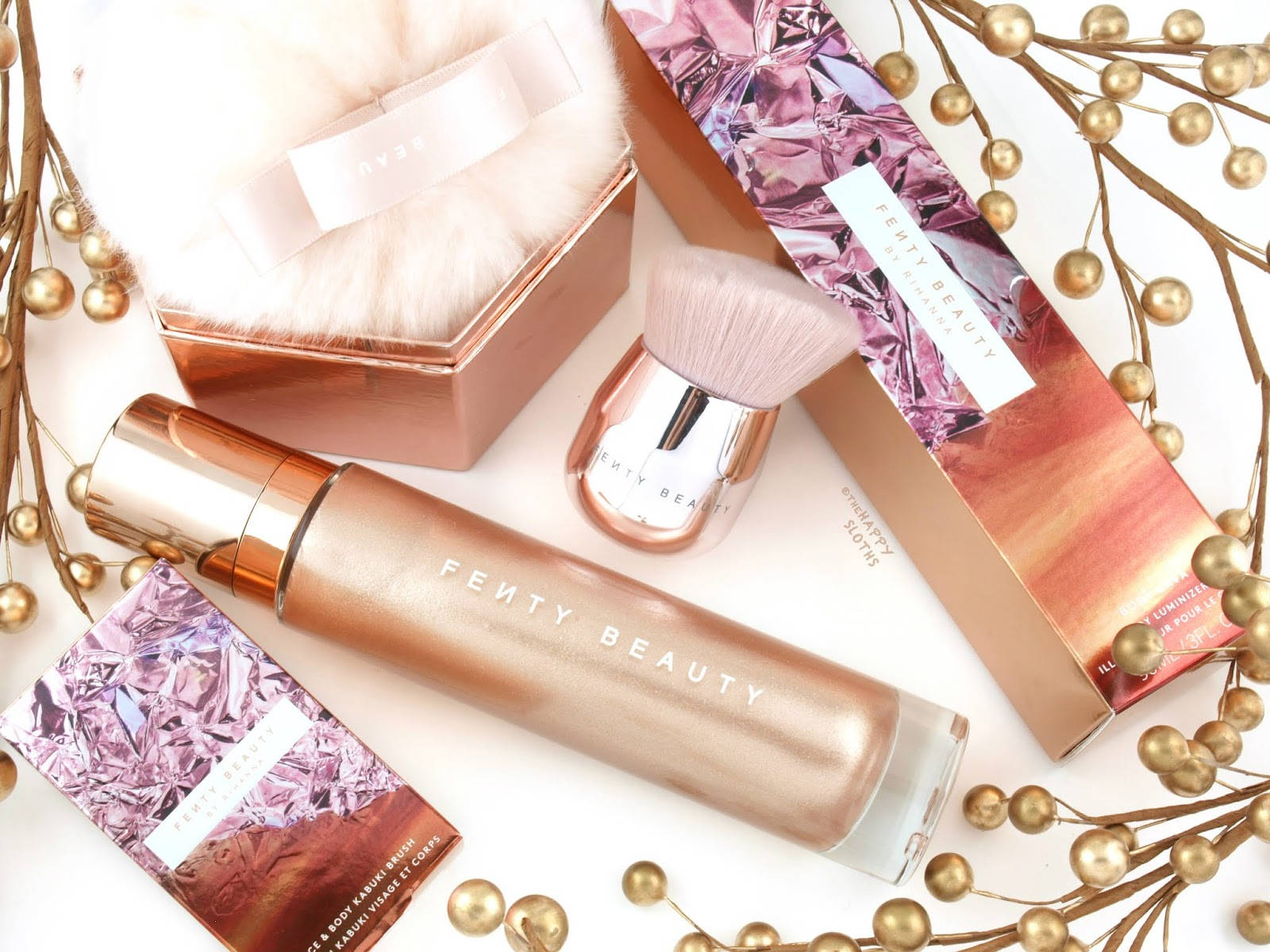 Fenty Beauty 化妝品被金色珠子環繞在白色表面上。