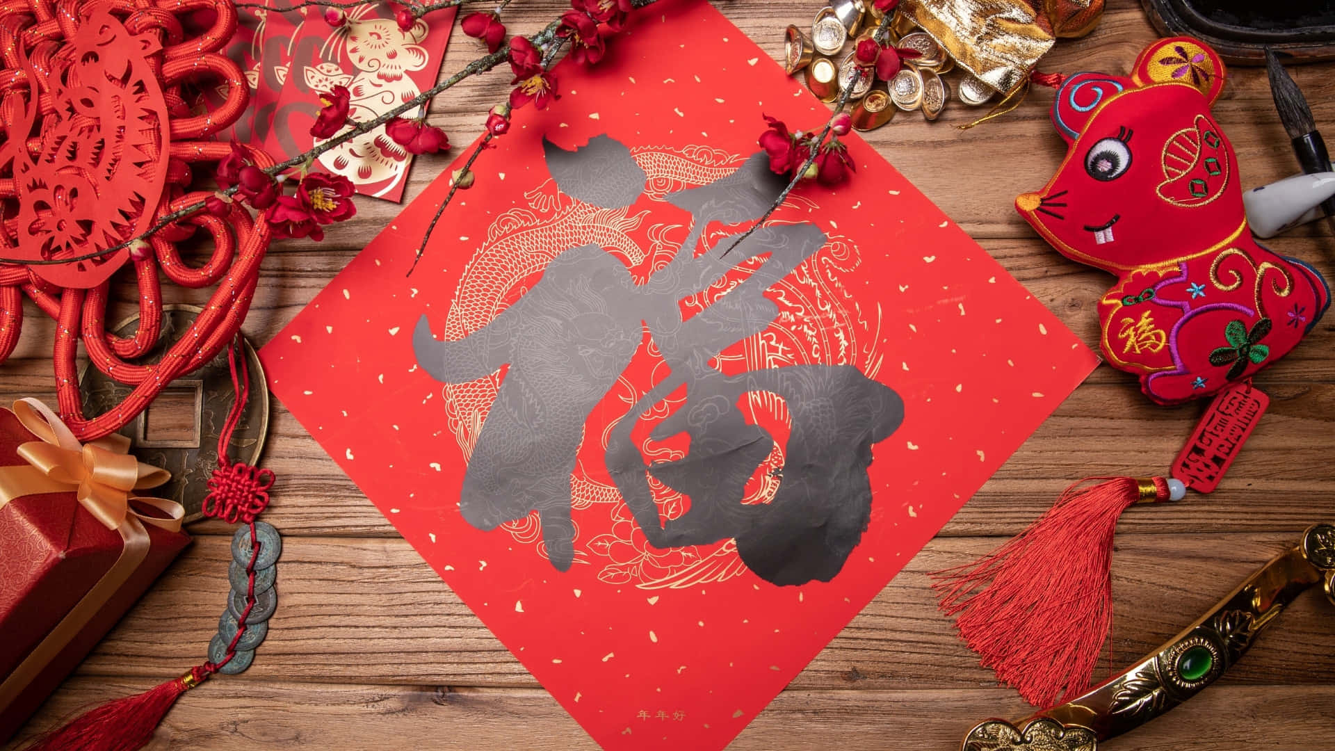 壁紙 — 一個喜慶的紅色農曆新年裝飾，在木質表面上有一個大的灰色「福」字，周圍環繞著複雜的剪紙流蘇和一個紅色老鼠公仔。
