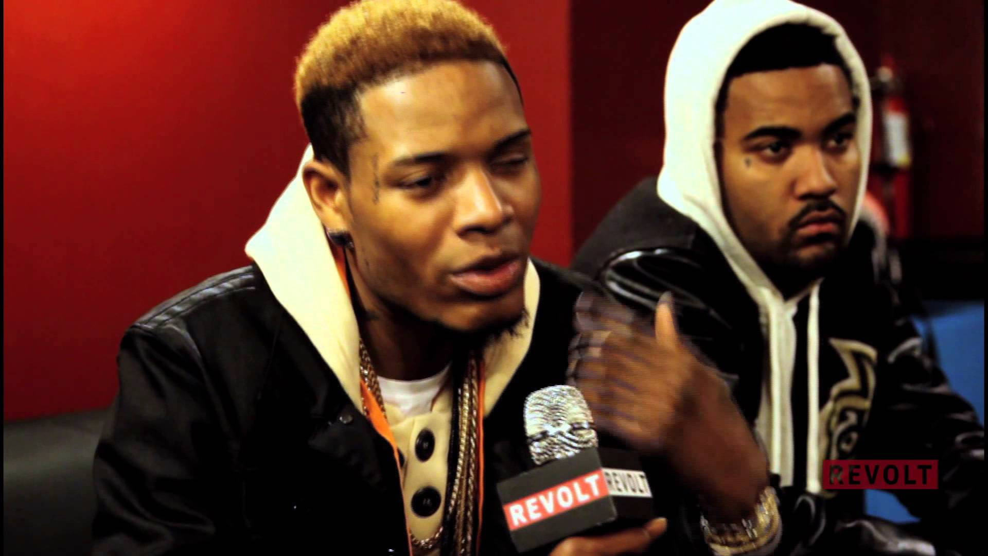 Fetty Wap 與Kanye West 壁紙 — 兩個穿著連帽衫的男人坐在紅牆前，其中一個對著Revolt麥克風說話，另一個專心聆聽。