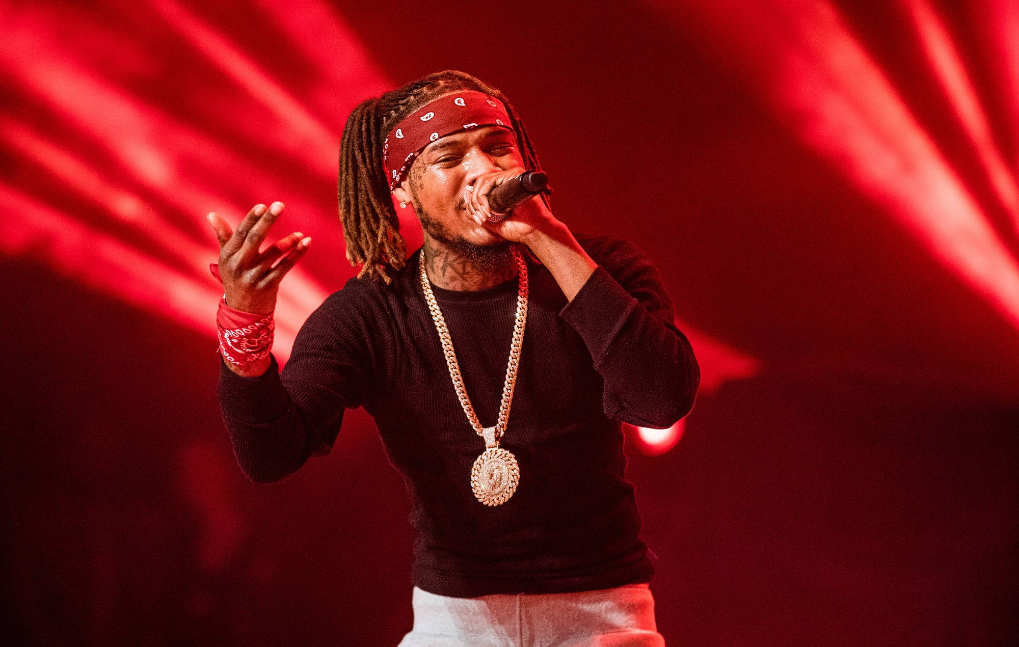 Fetty Wap演唱會 壁紙 — 一位梳著辮子頭、戴紅色頭巾的說唱歌手，在強烈的紅色舞台燈光下，熱情地對著麥克風演唱。