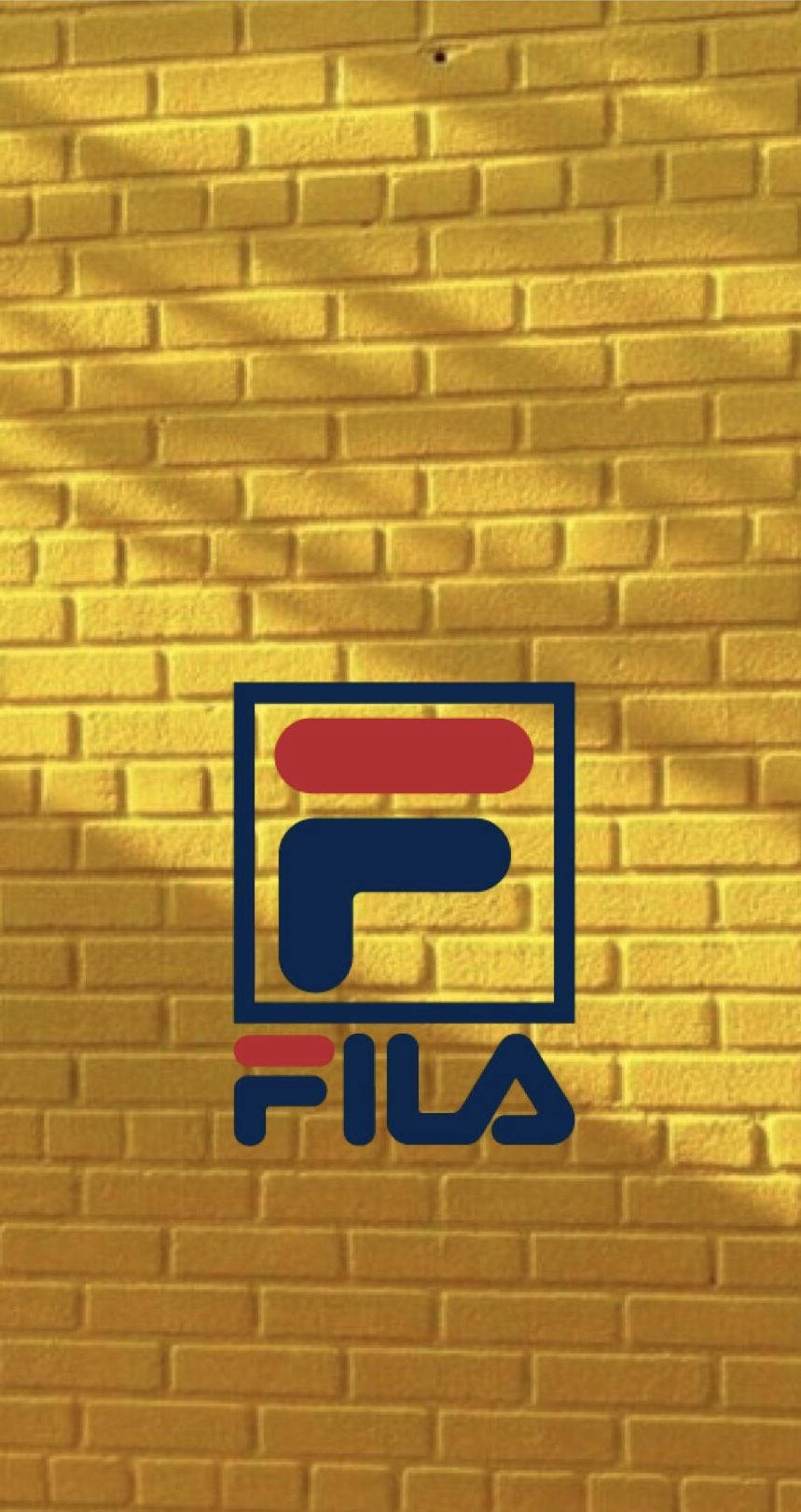Fila 標誌在黃磚牆上帶有陽光陰影