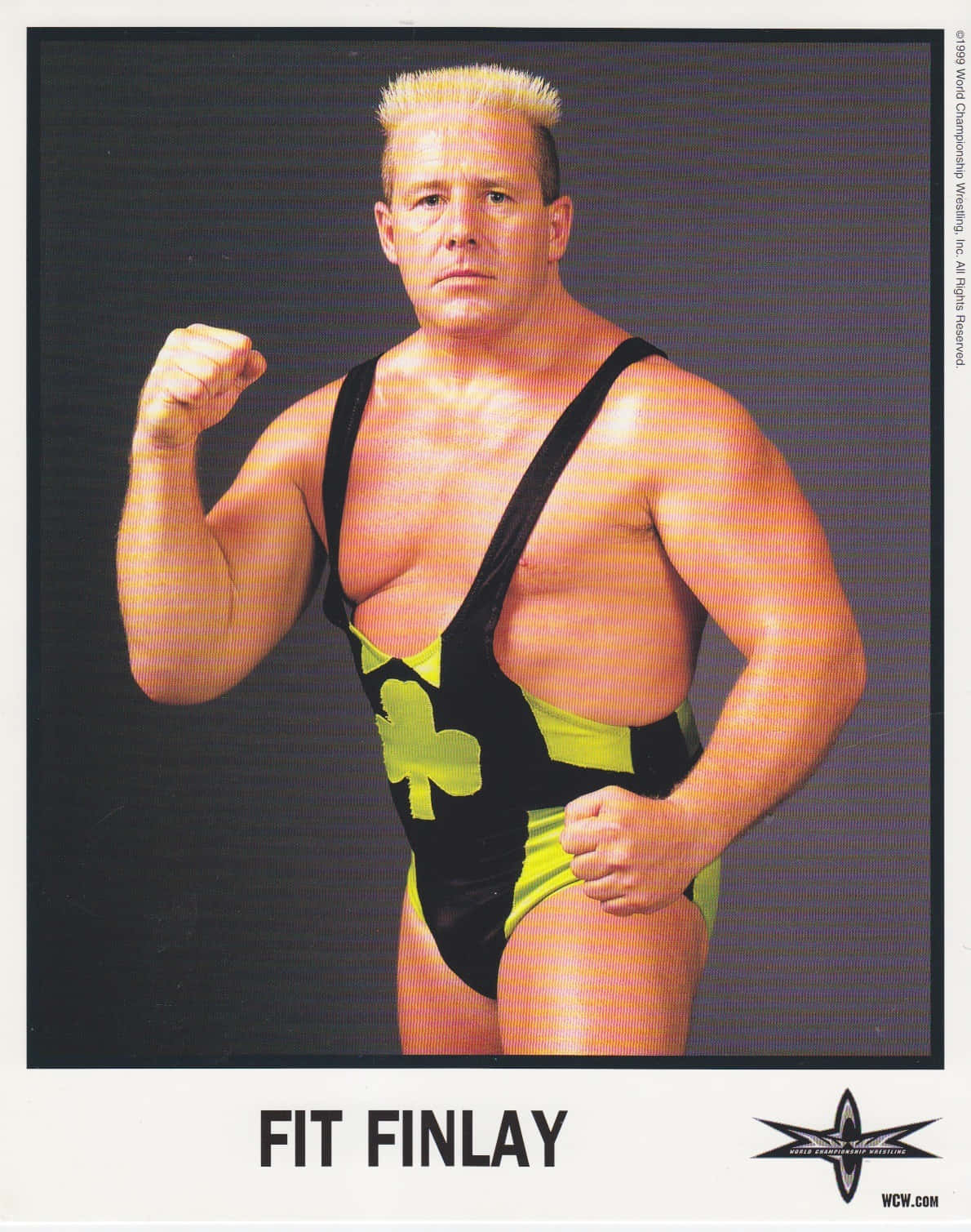 Fit Finlay WCW 1999 拳擊造型 壁紙 — 摔角手 Fit Finlay 身穿帶有三葉草標誌的黑色和螢光綠色短褲，在深色工作室背景前擺姿勢。