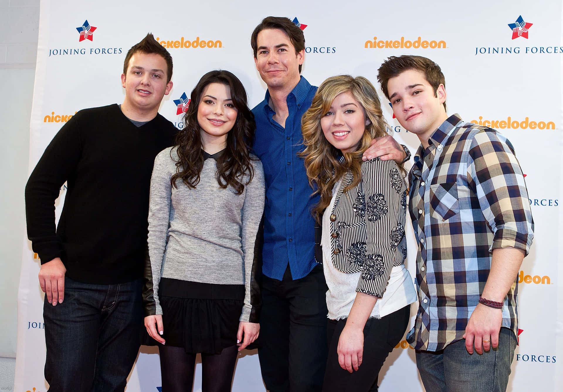  壁紙 — 五位微笑的年輕演員在Nickelodeon活動中一起擺姿勢，背景為品牌背景。