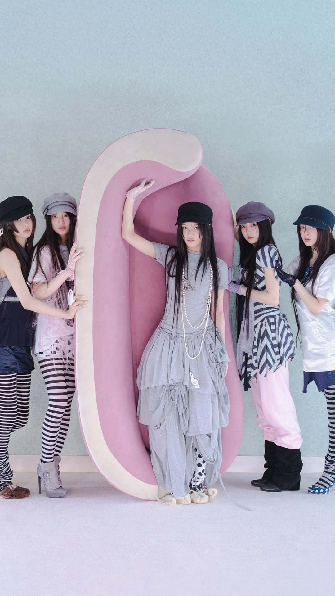  壁紙 — 五位年輕女性穿著時尚街頭服飾，在柔和青綠色牆壁前，圍繞一個巨大的粉紅色抽象雕塑擺姿勢。