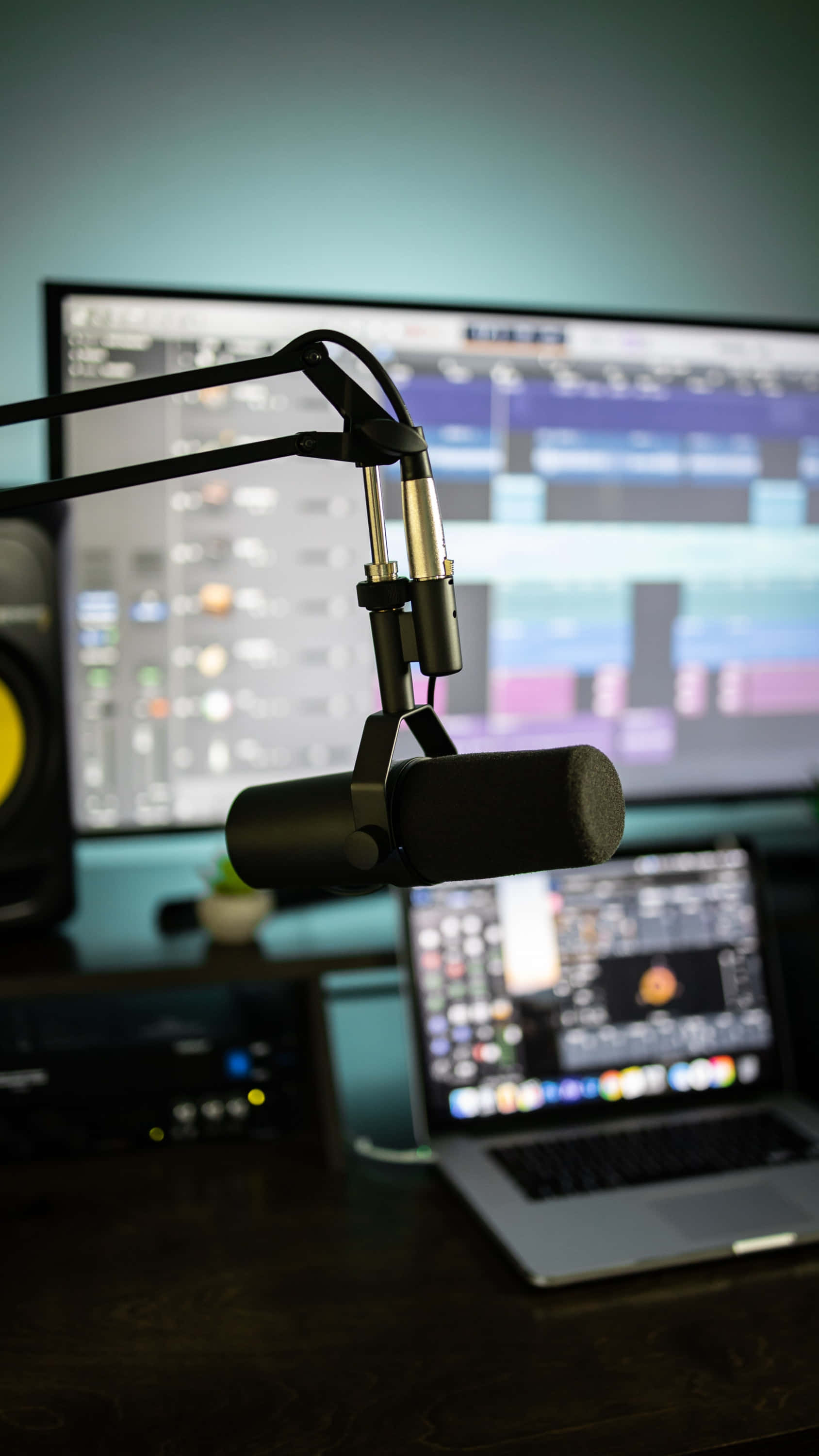 FL Studio 監視器 壁紙 — 一個專業的黑色錄音室麥克風安裝在支架臂上，前方是顯示音頻編輯軟件的電腦屏幕。