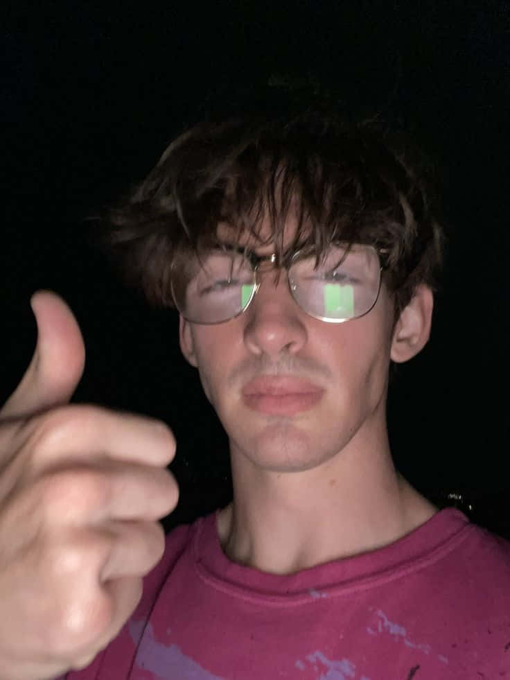 戴眼鏡的年輕男子在夜間做出豎起大拇指的手勢。