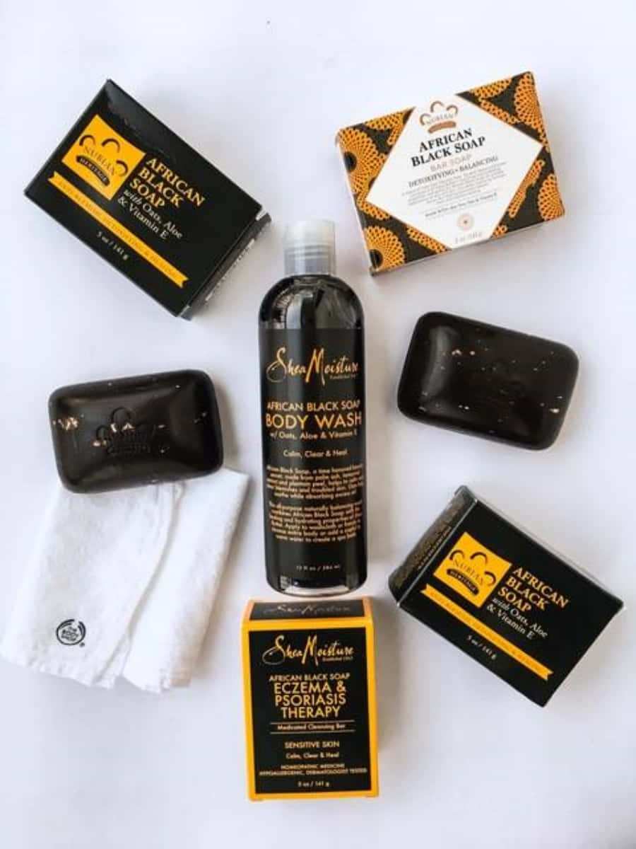 Black Soap 桌布 壁紙 — Shea Moisture African Black Soap 產品（包括沐浴皂條和瓶子）整齊排列在乾淨的白色表面上。