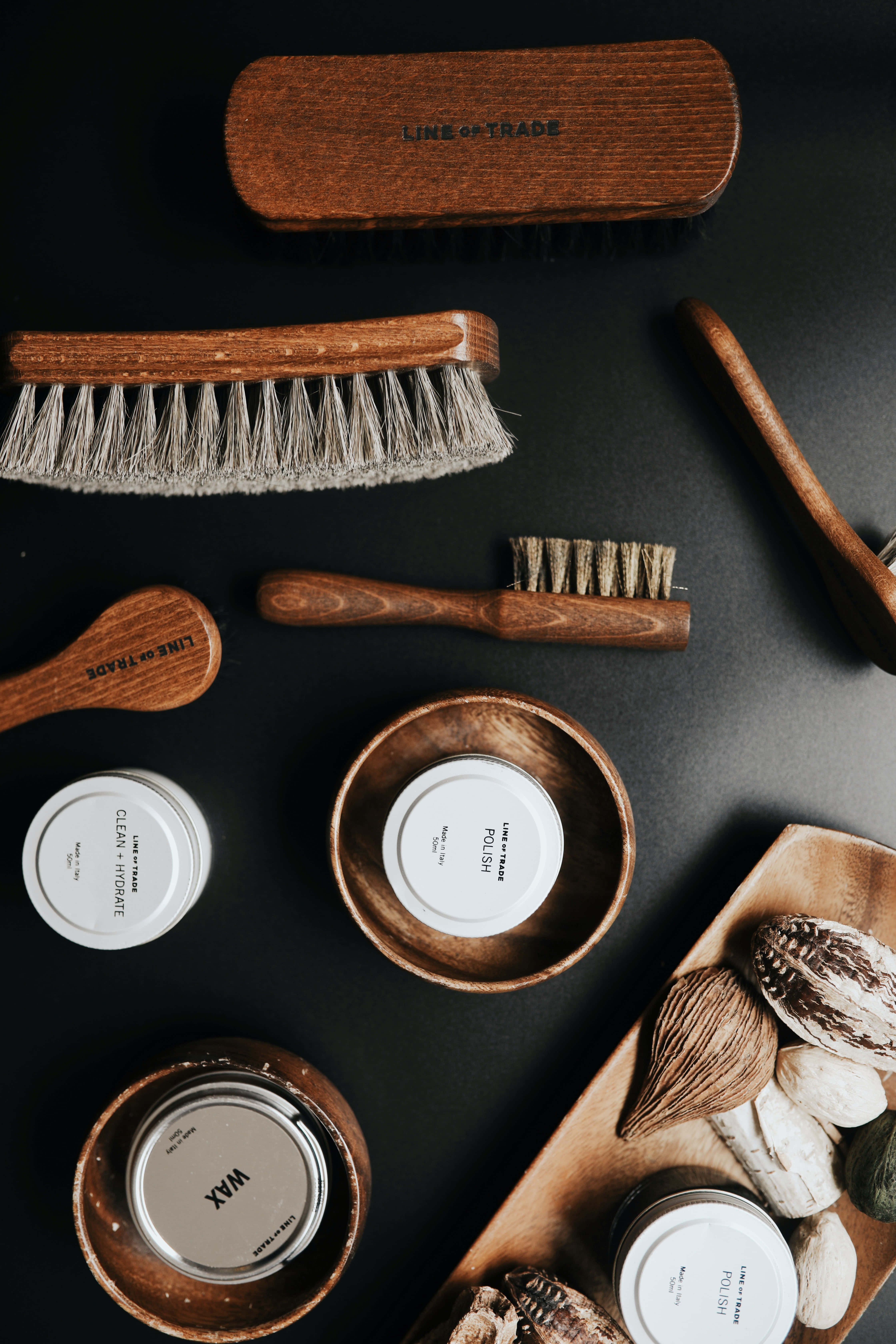 Barber 桌布 壁紙 — 在深色表面上平鋪擺放木製鞋護理刷和標籤的蠟拋光罐。
