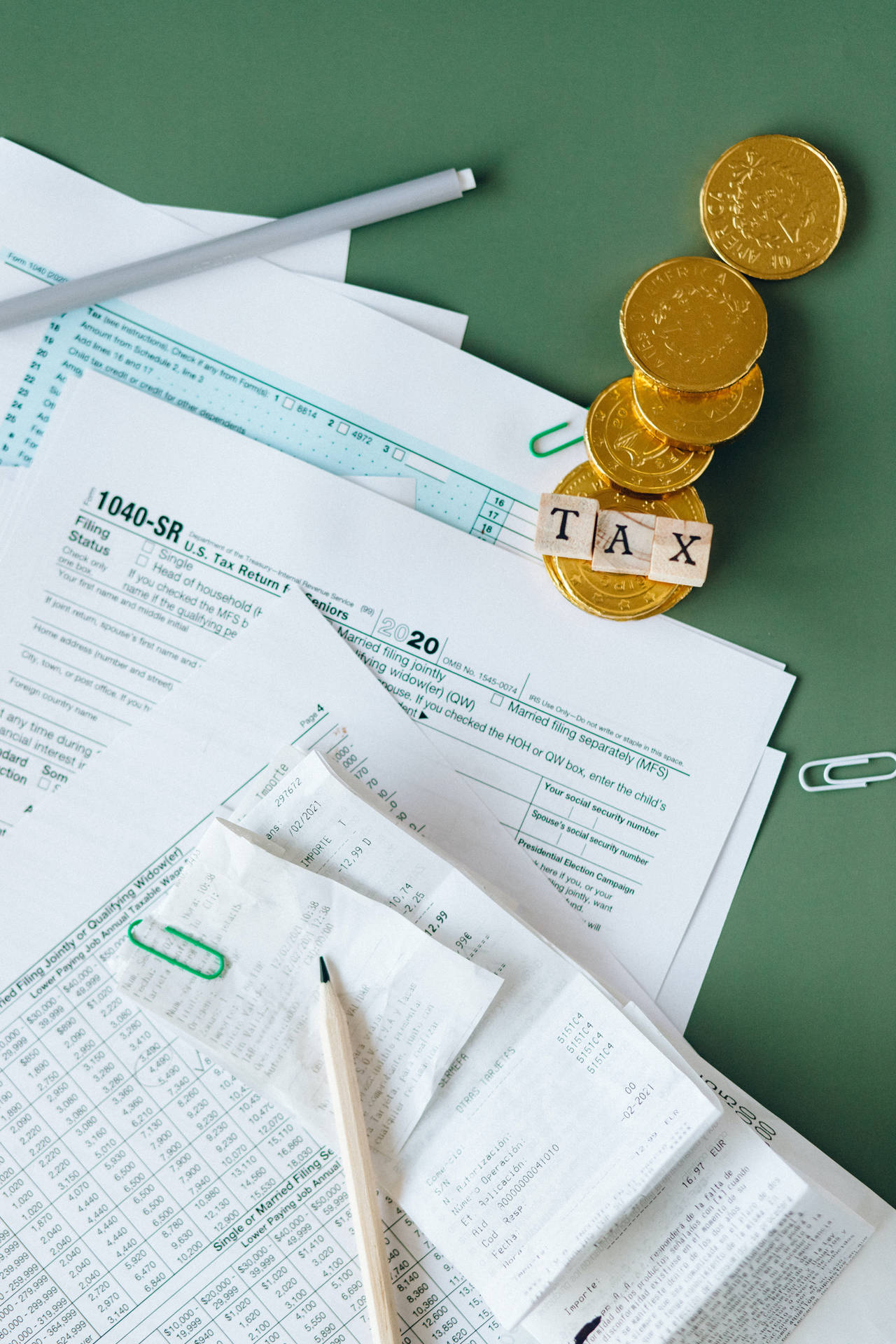 稅務文件 收據 金幣 拼出「稅」字 在綠色桌上