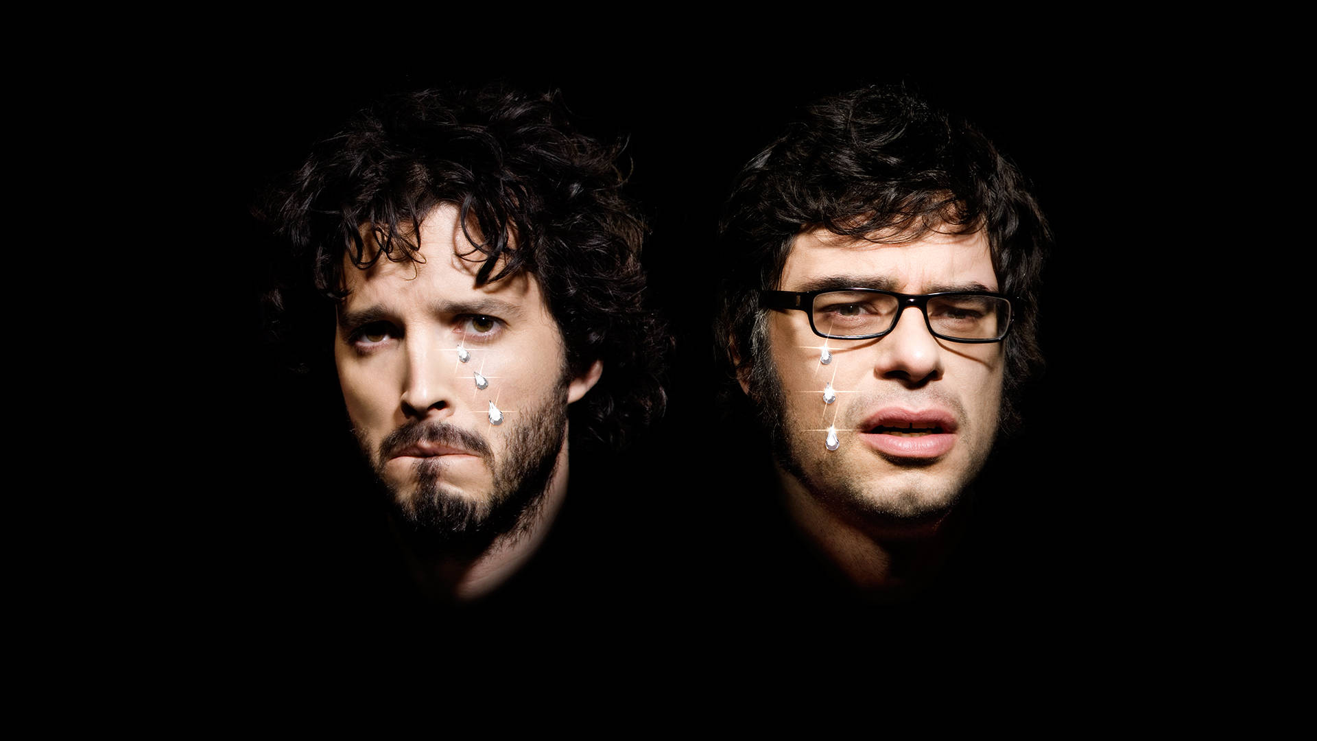 Flight Of The Conchords 哭泣肖像 壁紙 — 兩名捲髮戴眼鏡的男子在黑色背景前，臉上帶有白色水滴效果，凝視著鏡頭。
