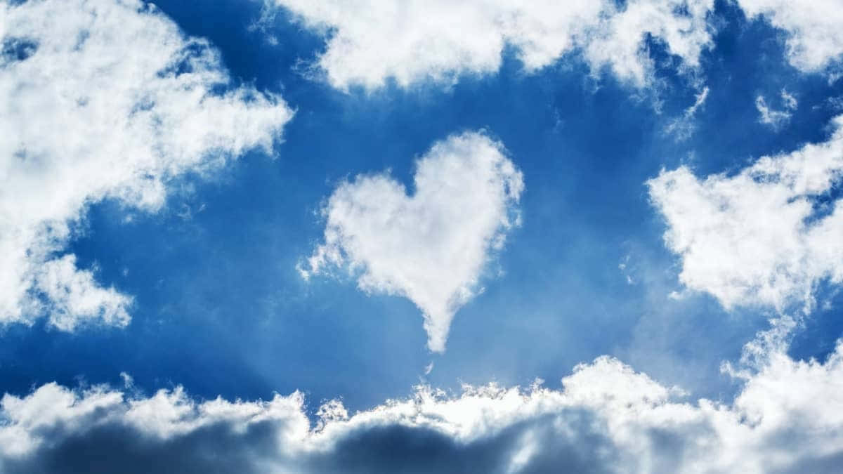 I Love God 桌布 壁紙 — 一朵蓬鬆白色心形雲朵在點綴著柔和雲朵的鮮豔藍天中寧靜漂浮。
