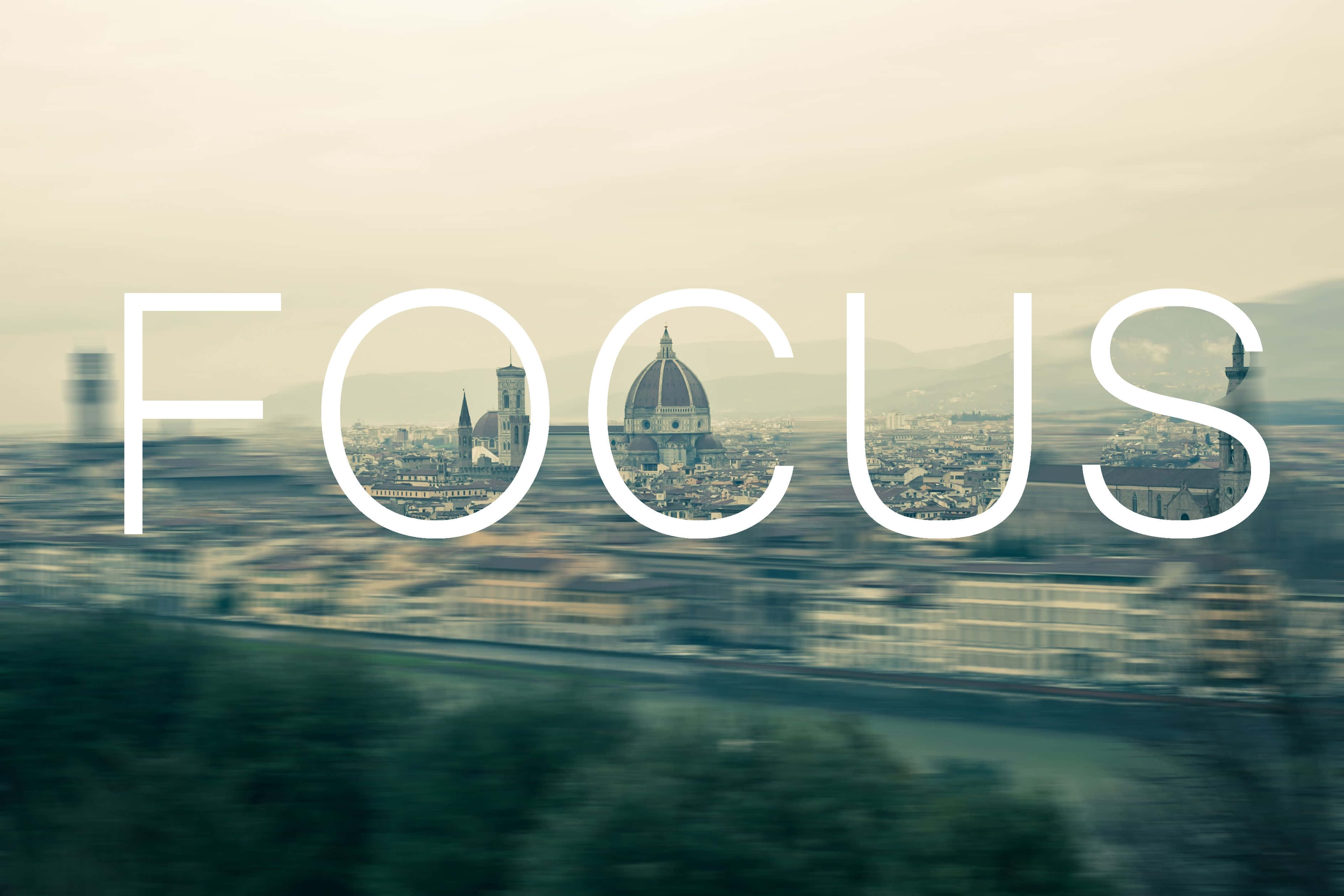 Focus 桌布 壁紙 — 「focus」呢個字疊加喺模糊嘅城市景觀上，佛羅倫斯嘅圓頂透過字母可見。