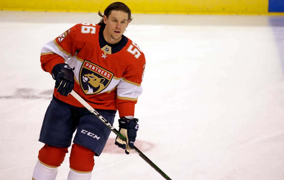 Erik Haula 桌布 壁紙 — 一位專注的曲棍球運動員穿著紅色Panthers球衣，在明亮的冰場上持桿滑行。