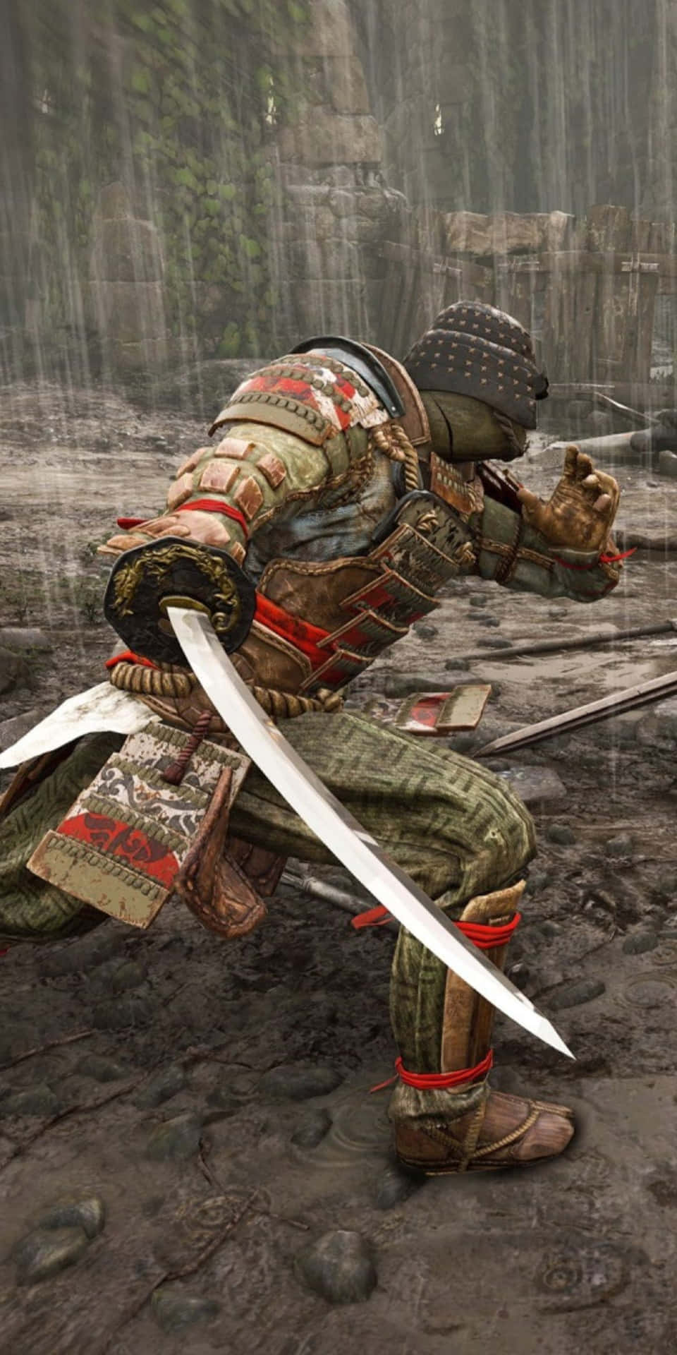 身穿雨濕鎧甲的武士蹲在石頭廢墟中手持武士刀。