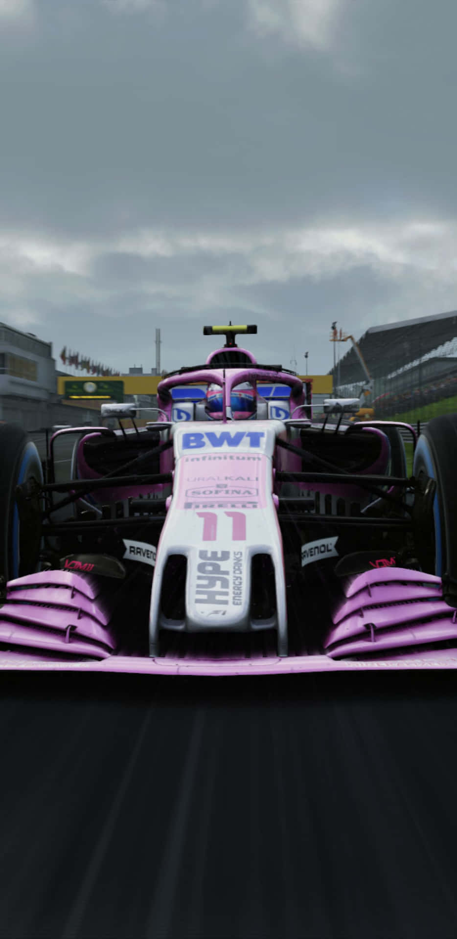 粉紅色和白色的 Formula 1 賽車在陰天下的賽道上比賽。