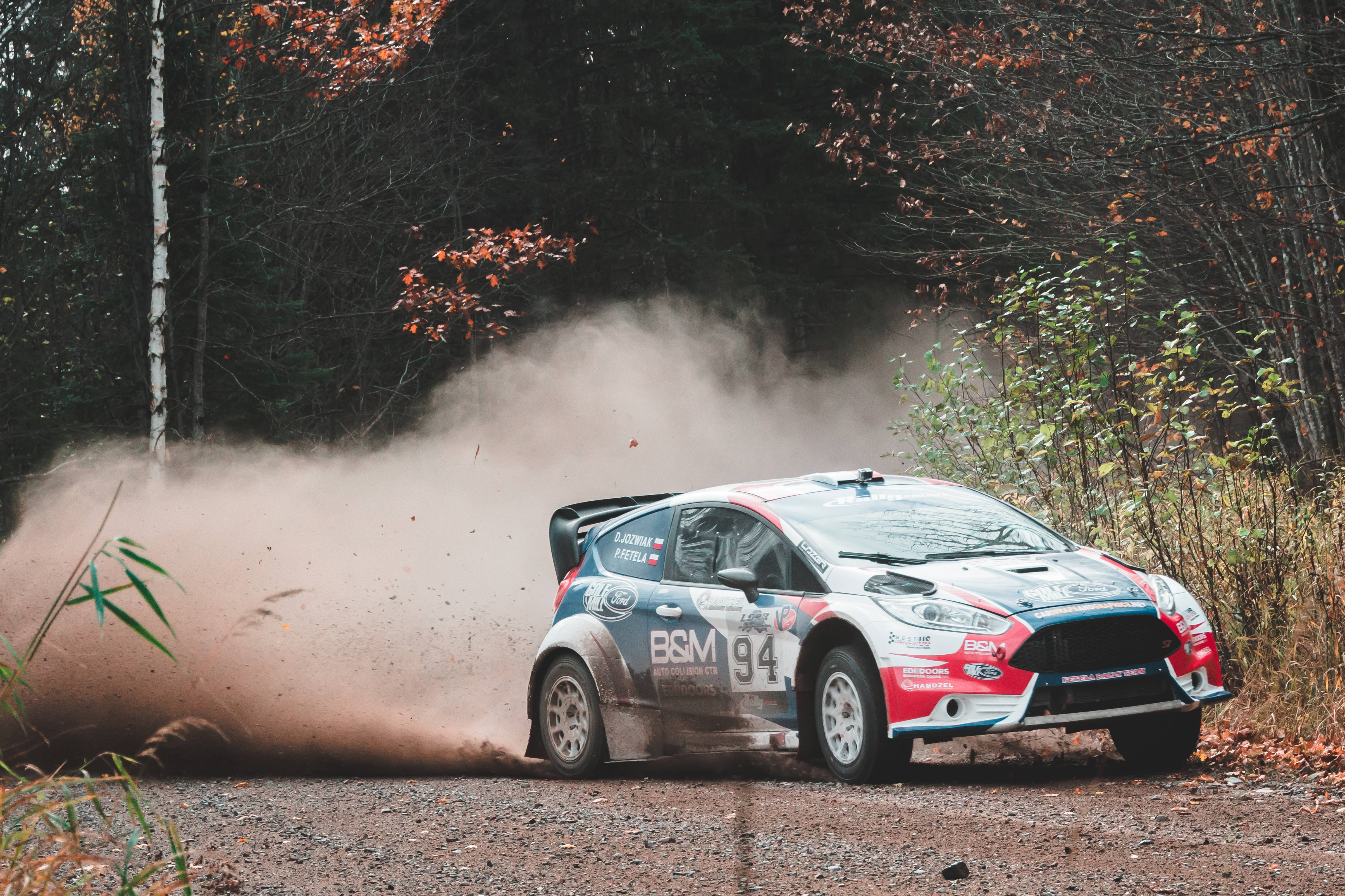 Ford Fiesta RS WRC 在 Dirt Rally 中的激烈賽道 壁紙 — 一輛拉力賽車在秋日林間道路上疾馳，揚起塵土。