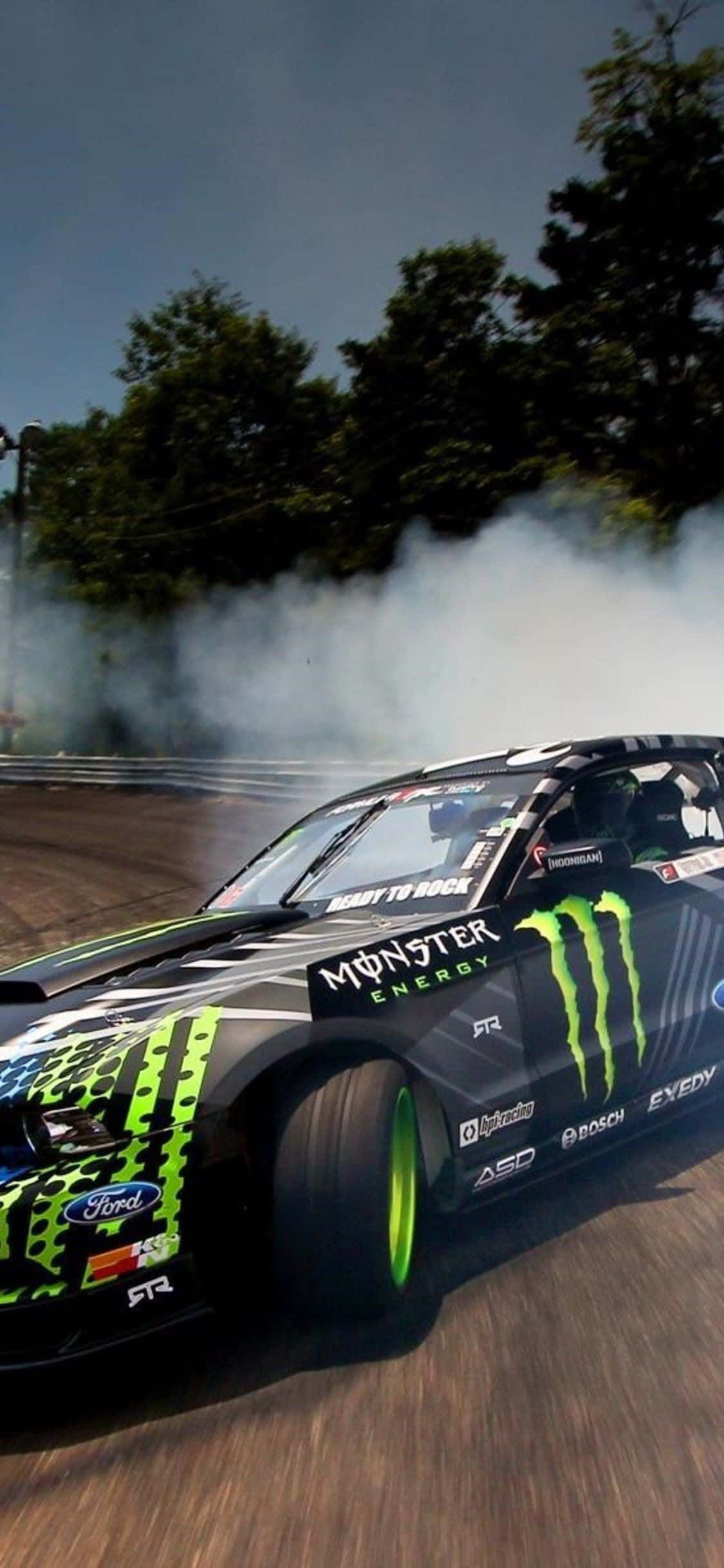 Ford Mustang iPhone X Forza Motorsport 7 背景 壁紙 — 一輛黑色和綠色的Monster Energy Ford漂移車在多雲的天空下的賽道上揚起煙霧。
