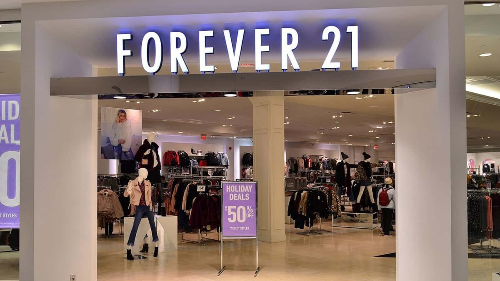 Forever 21 最新潮流最高達 7 折優惠 壁紙 — 燈光明亮的Forever 21商店入口，展示著穿著時尚服裝的人體模型和一個顯眼的50%假期優惠標誌。