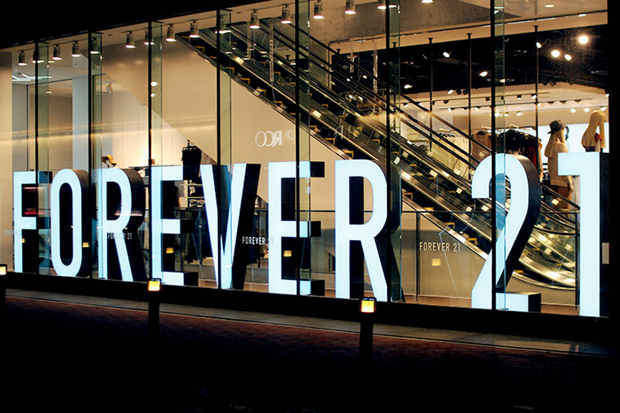 Forever 21 服裝品牌 壁紙 — 大型發光嘅「FOREVER 21」字母照亮咗夜晚嘅玻璃門面商店，入面見到扶手電梯同人體模型。