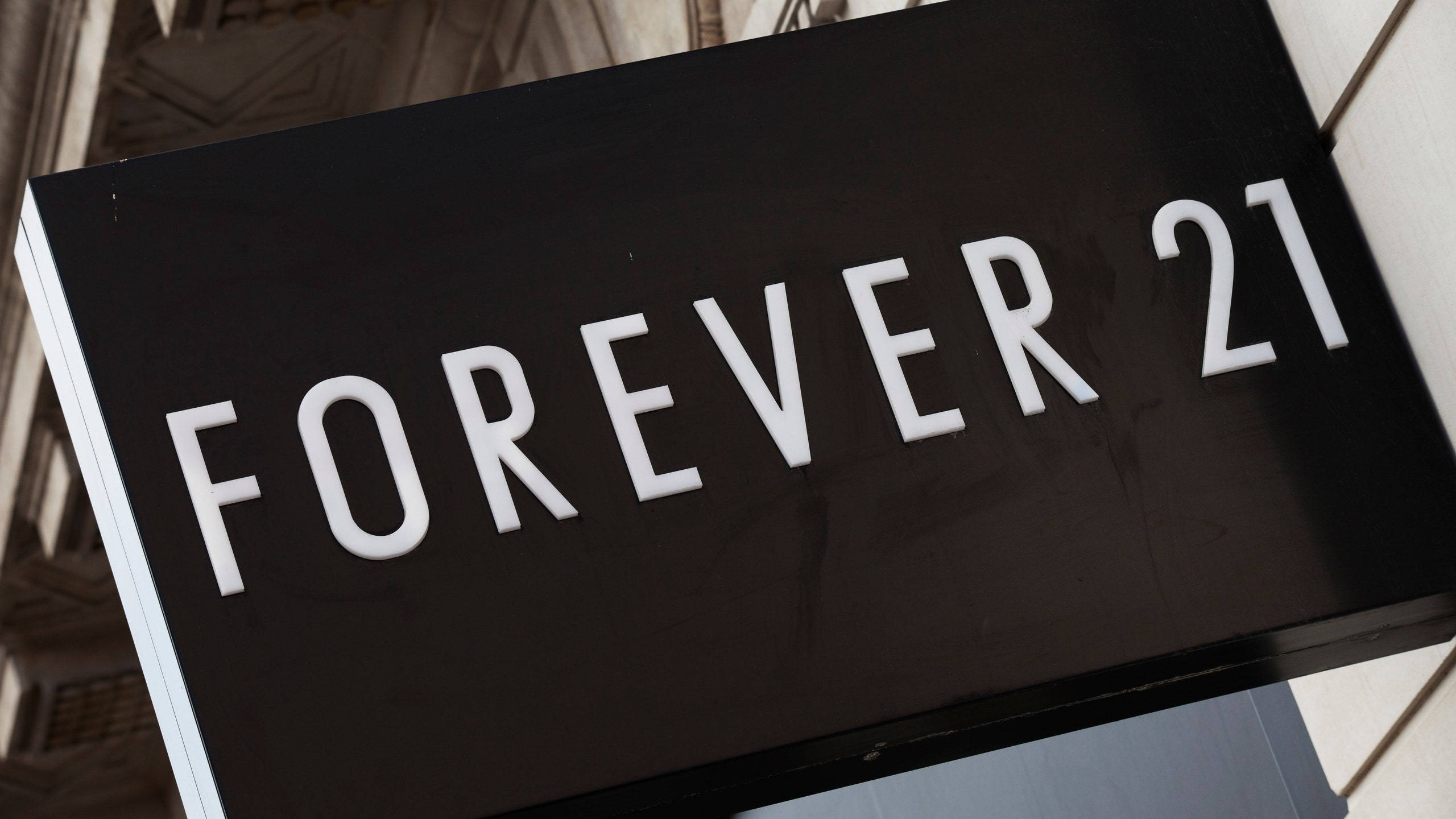 Forever 21 黑白招牌 壁紙 — 建築物外牆上安裝的黑色Forever 21商店招牌特寫，帶有粗體白色字體。