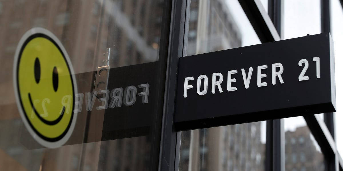Forever 21建築招牌 壁紙 — 特寫一個黑色 Forever 21 商店招牌，上面有白色字體，安裝在玻璃店面，上面有一個黃色笑臉貼紙。