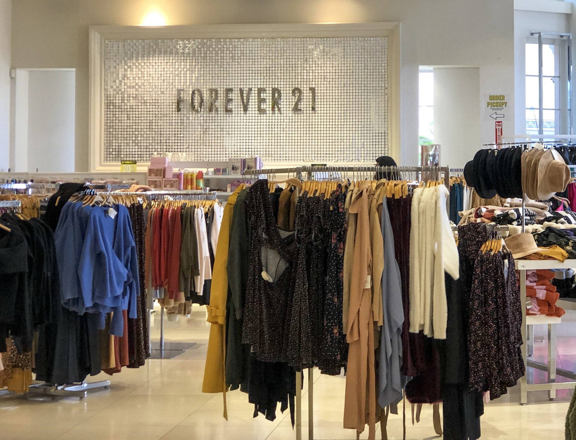 Forever 21時尚店 壁紙 — 光線明亮的Forever 21店內，展示著色彩繽紛的服裝架，背景是閃爍的馬賽克牆。