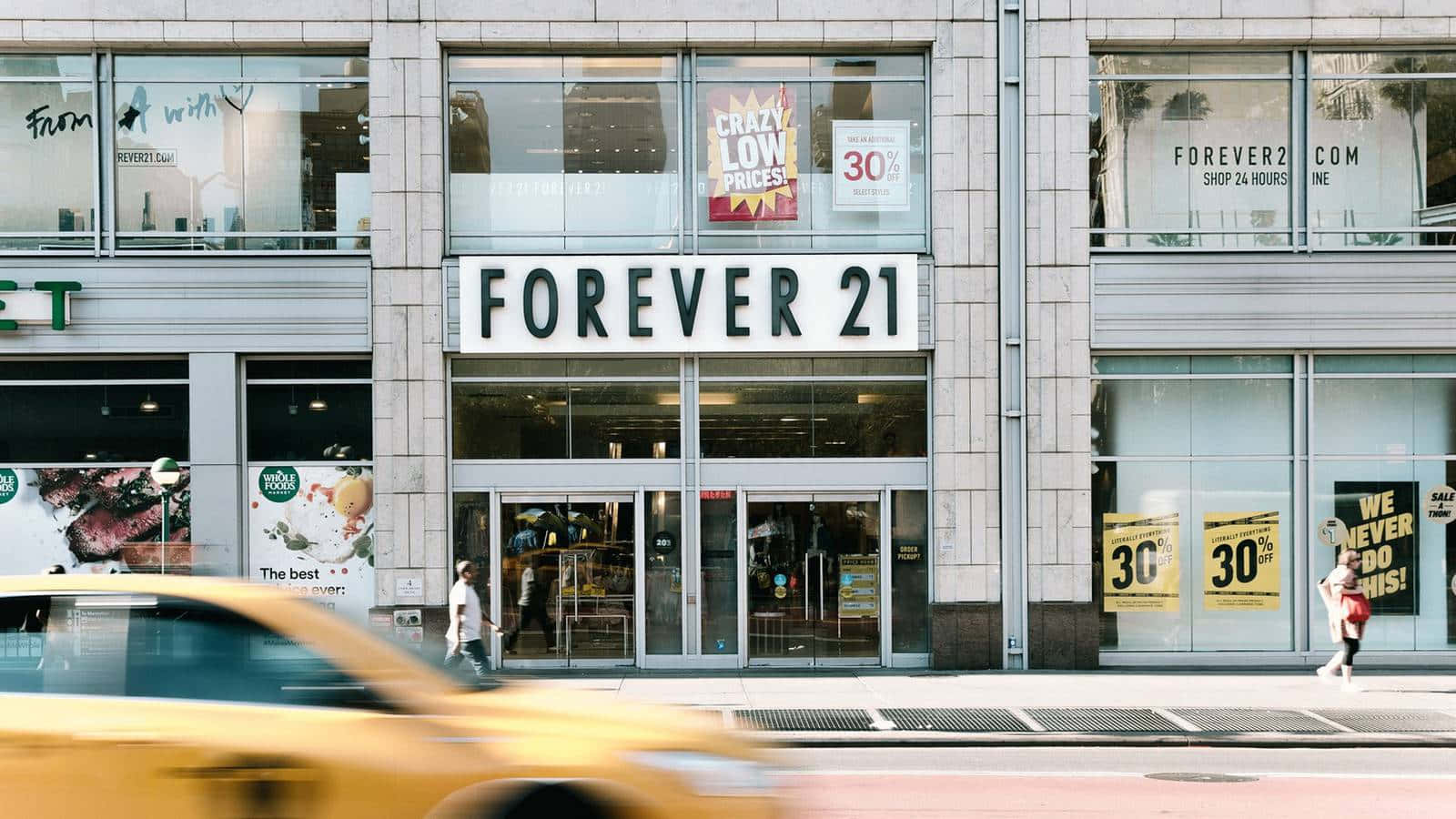 黃色的士高速駛過一間帶有減價標誌的Forever 21零售店。