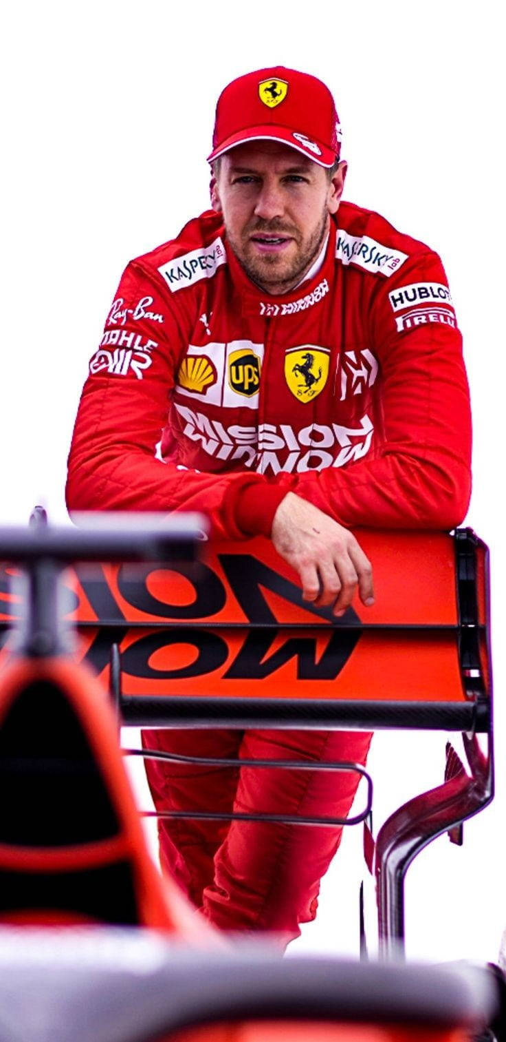 身穿紅色賽車服的法拉利F1車手靠在賽車前翼上。