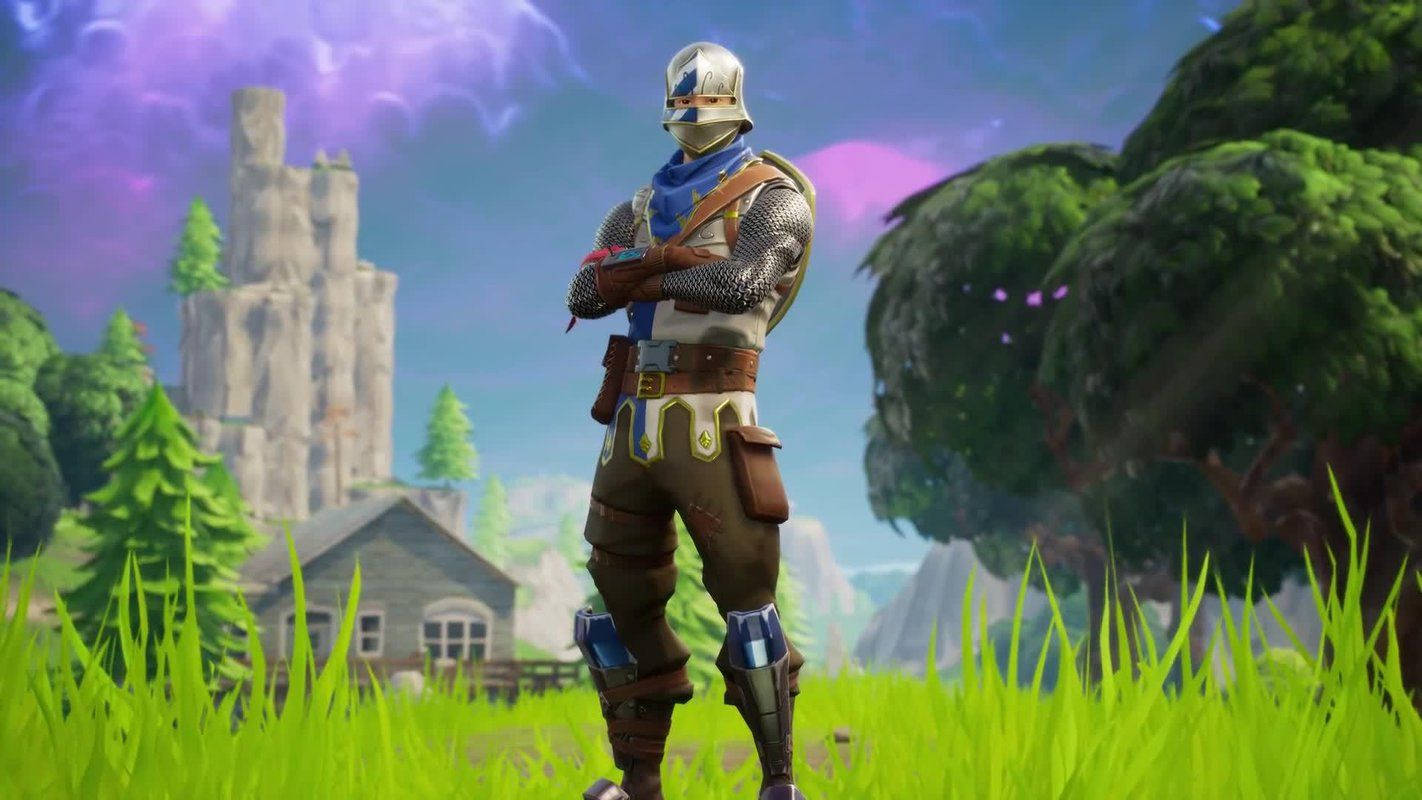 《Fortnite 競技場》藍騎士立於草地 壁紙 — 一名身穿盔甲的騎士自信地站在色彩繽紛的田野中，背景有城堡和樹木，天空呈紫色。
