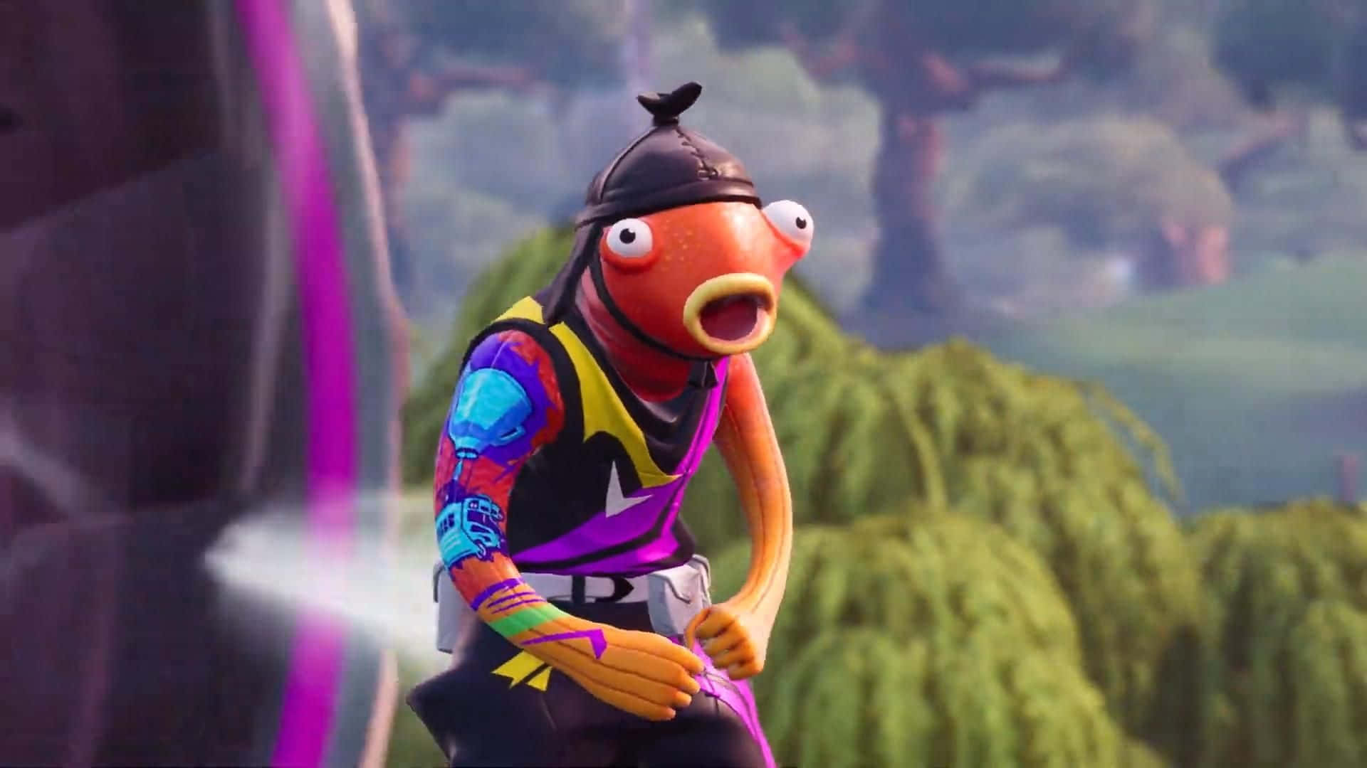 在《Fortnite》手機版戰鬥中化身Fishstick 壁紙 — 一個卡通魚角色，戴著黑色帽子，穿著色彩繽紛的服裝，站在充滿活力的戶外場景中，周圍有綠色植物和紫色燈光效果。