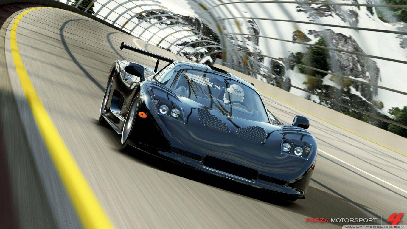 Forza 7 賽車競速 壁紙 — 一輛時尚的黑色跑車沿著蜿蜒的山路飛馳，背景是白雪覆蓋的山峰和玻璃隧道。