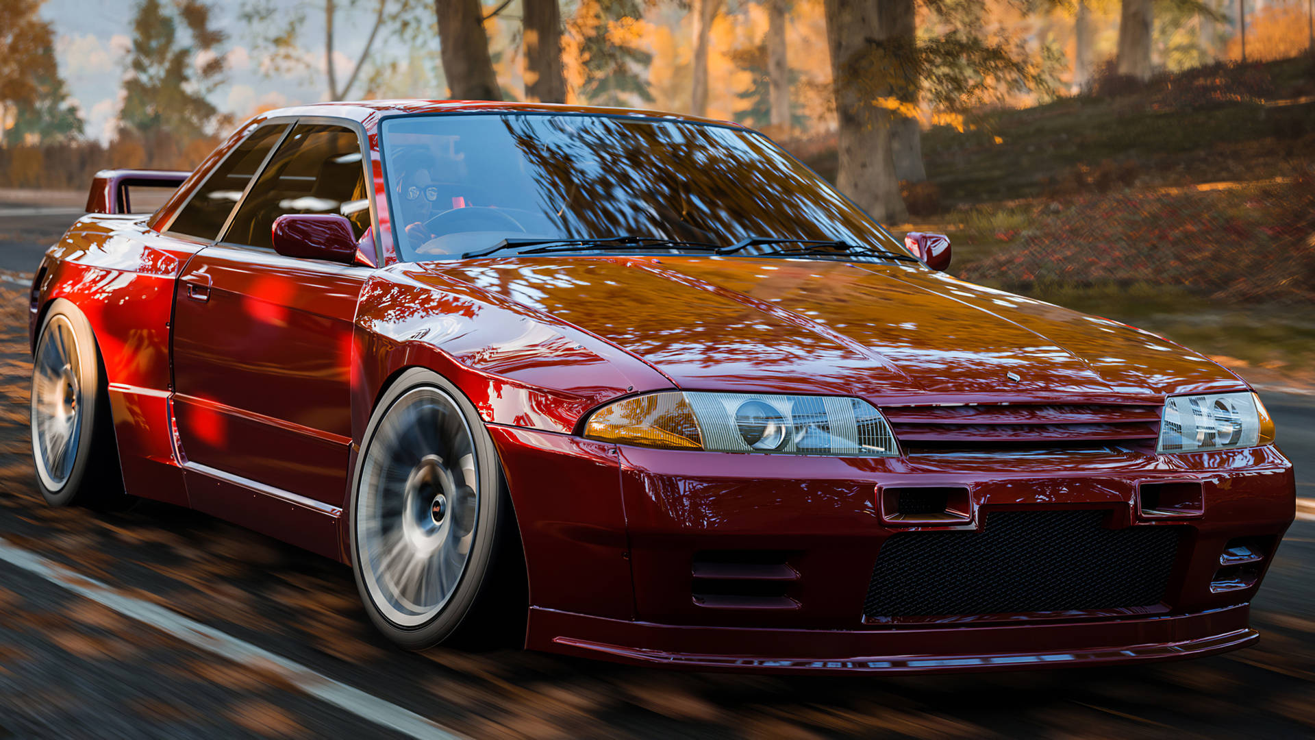 紅色日產Skyline R34在秋季黃金時段於森林道路上飄移。