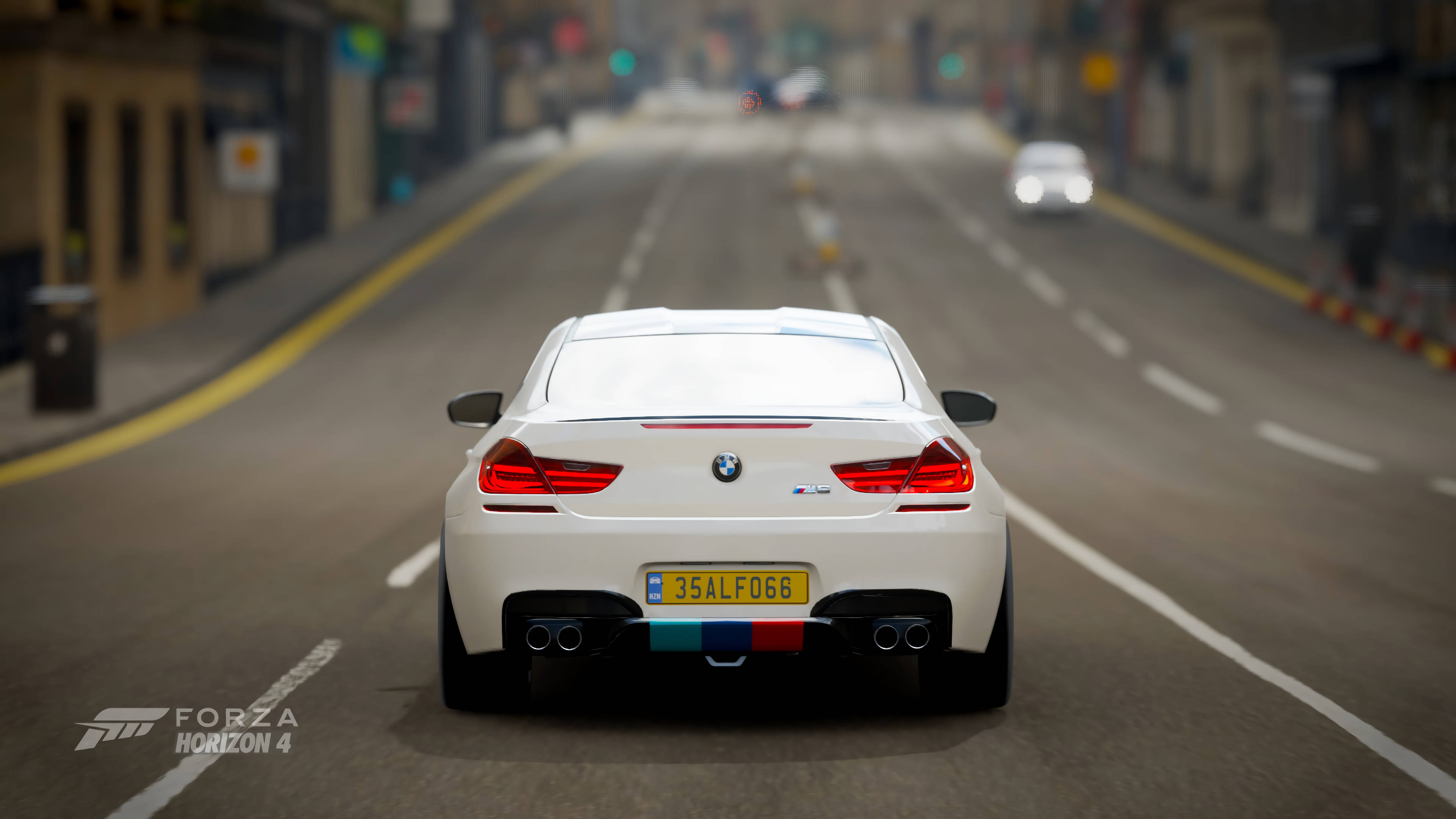 Forza Horizon 4 白色寶馬 壁紙 — 一輛白色BMW M6開篷車在霧氣瀰漫的市區街道上行駛，背景是模糊的交通和商店櫥窗。