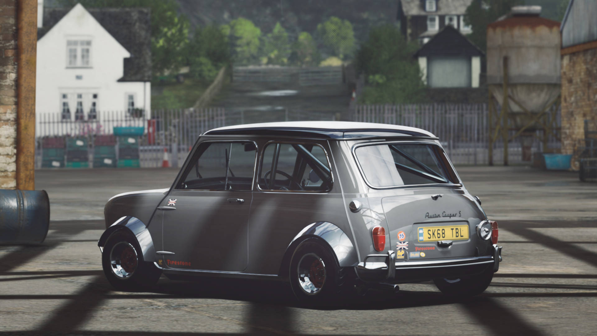 銀色經典Mini Cooper S賽車在工業庭院中，背景有石建築物和綠色植物。