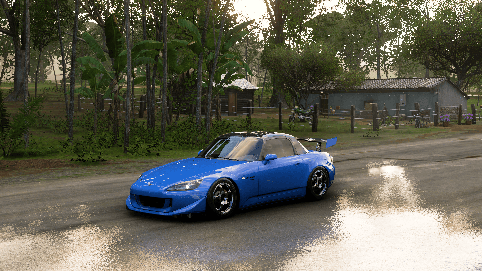 Forza Horizon - 本田S2000 壁紙 — 一輛充滿活力的藍色改裝跑車在黎明時分沿著一條濕潤的鄉村道路滑行，兩旁是茂密的綠樹和質樸的小屋。