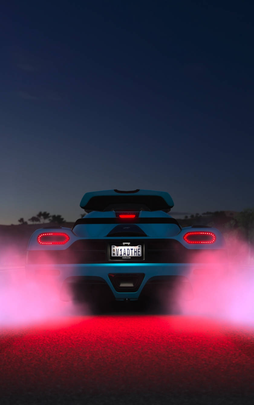紅黑Forza iPhone壁紙 壁紙 — 一輛藍色跑車在戲劇性的夜間場景中燒著紅色輪胎，排氣管發光，天空漆黑。