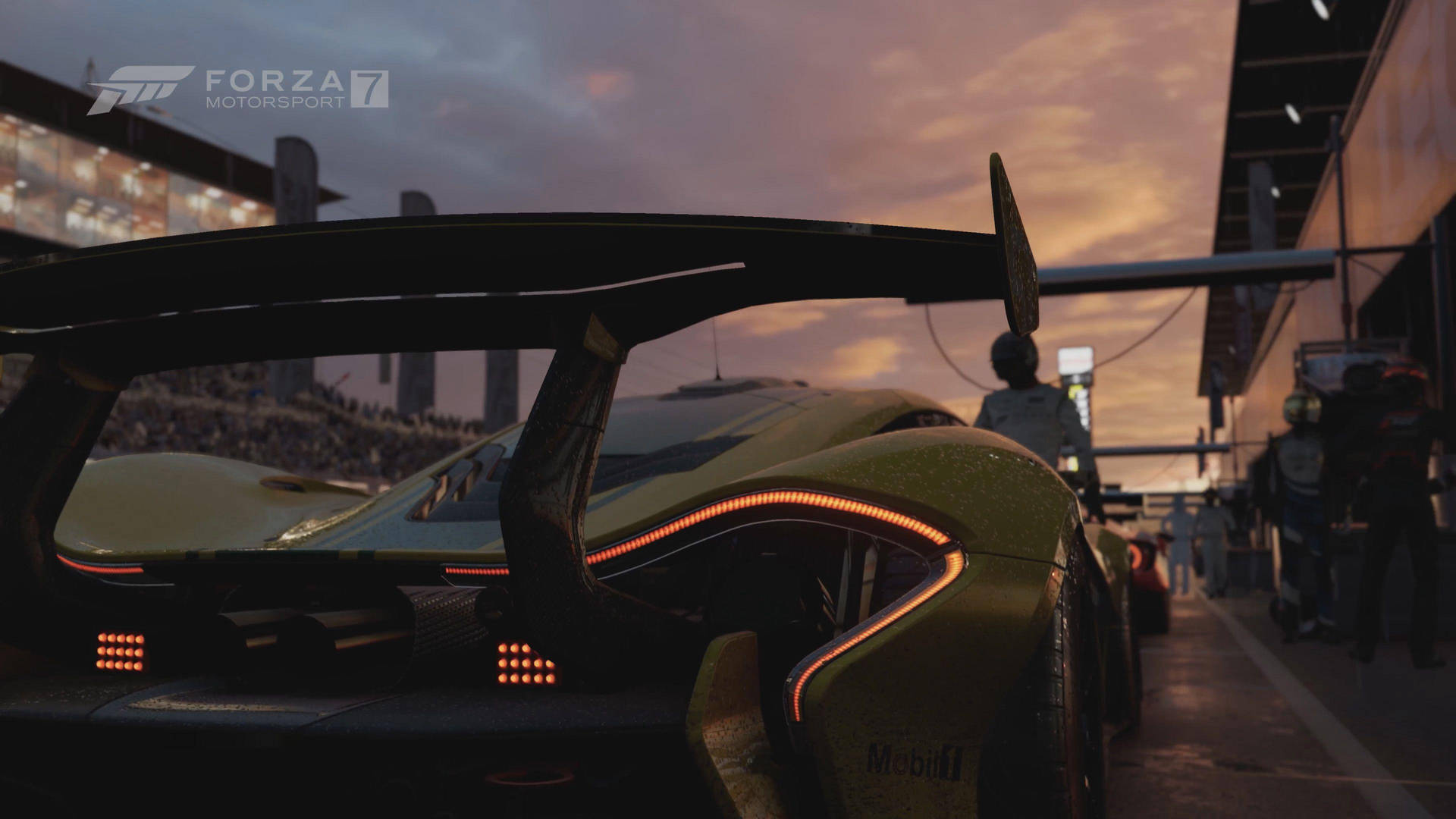 Forza Motorsport 7 黃綠賽車激烈競速 壁紙 — 一輛金色賽車帶有發光的橙色燈光，在日落時停泊在維修區車道，背景有群眾。