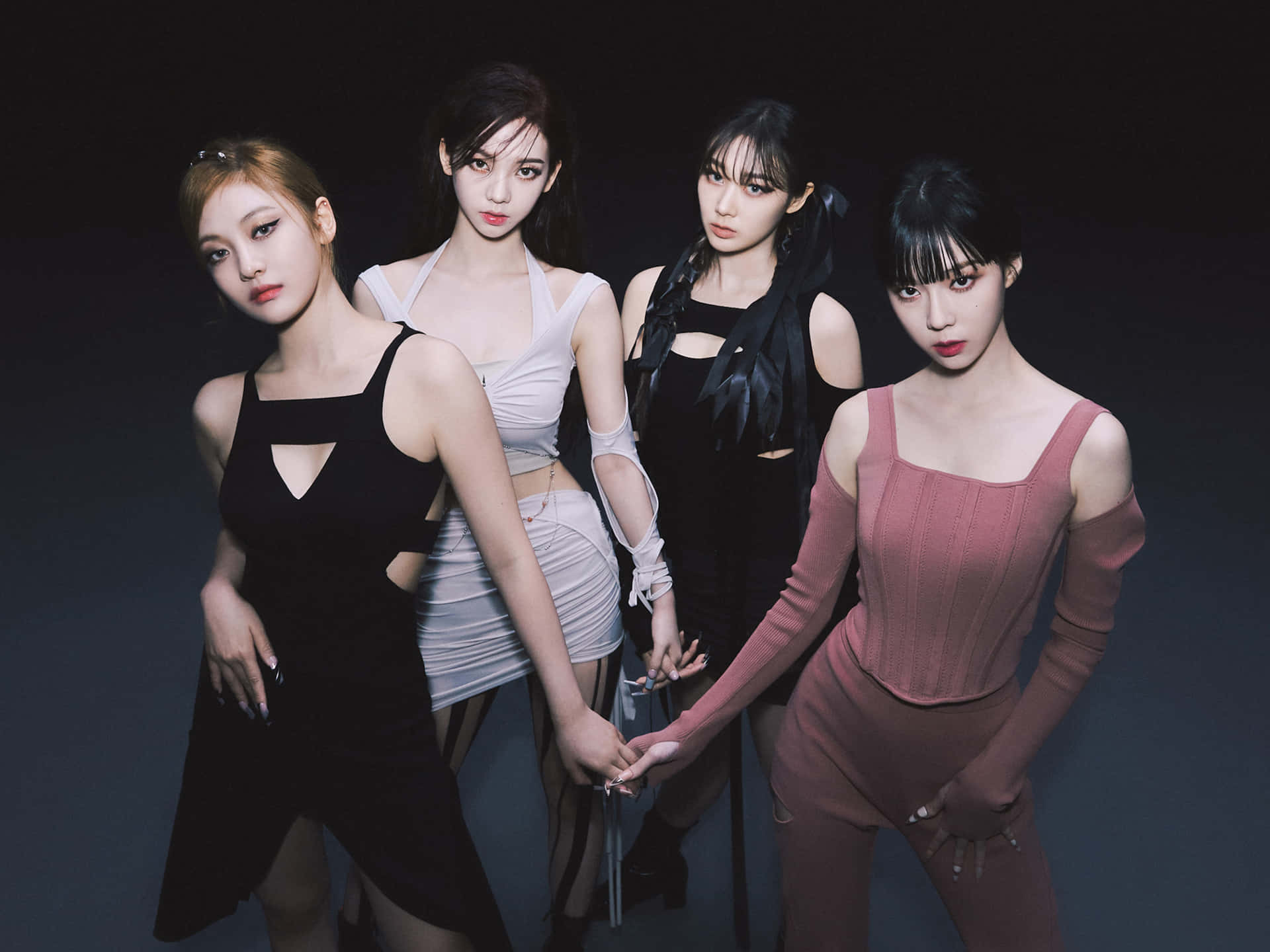四位時尚女性穿著現代服裝在黑暗的攝影棚環境中擺姿勢。