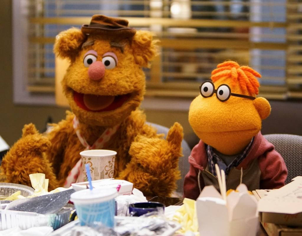 Fozzie Bear 與 Scooter 壁紙 — Fozzie Bear 同一個戴眼鏡嘅橙色木偶坐喺一張亂七八糟嘅枱邊，枱上放滿外賣食物同飲品。