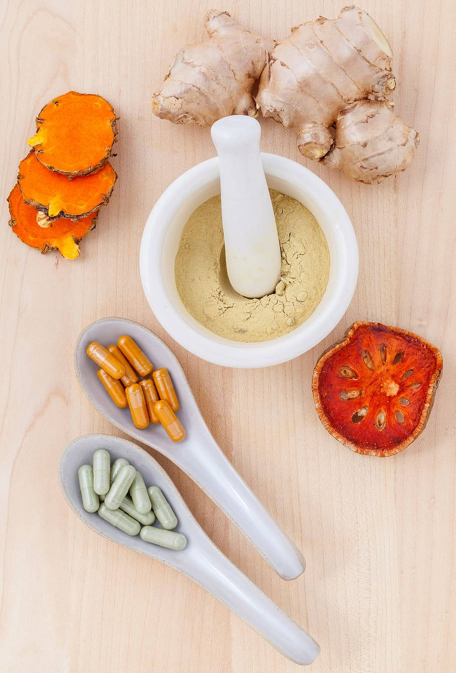 草本成分包括生薑、薑黃和膠囊，排列在木質表面上。
