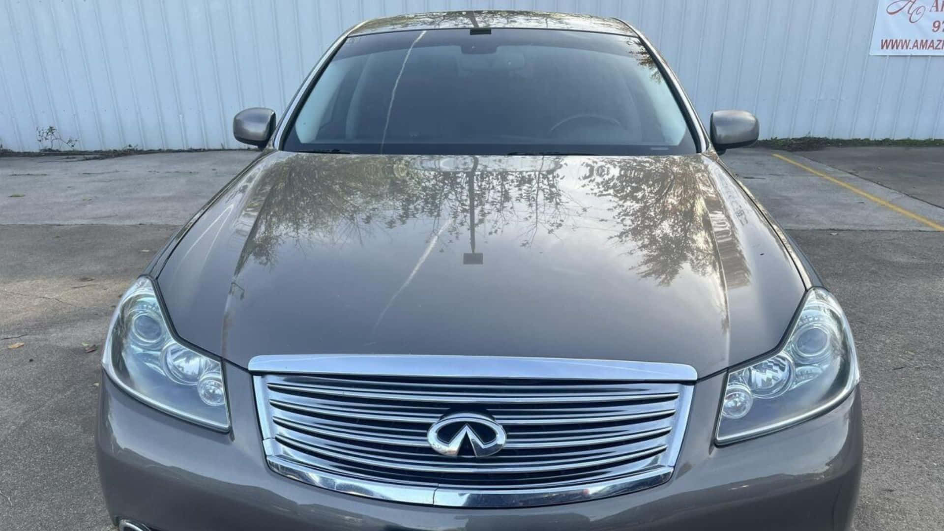 Infiniti M35 桌布 壁紙 — 一輛時尚灰色Infiniti房車停放在戶外的正面視圖，引擎蓋上反射著樹木的倒影。
