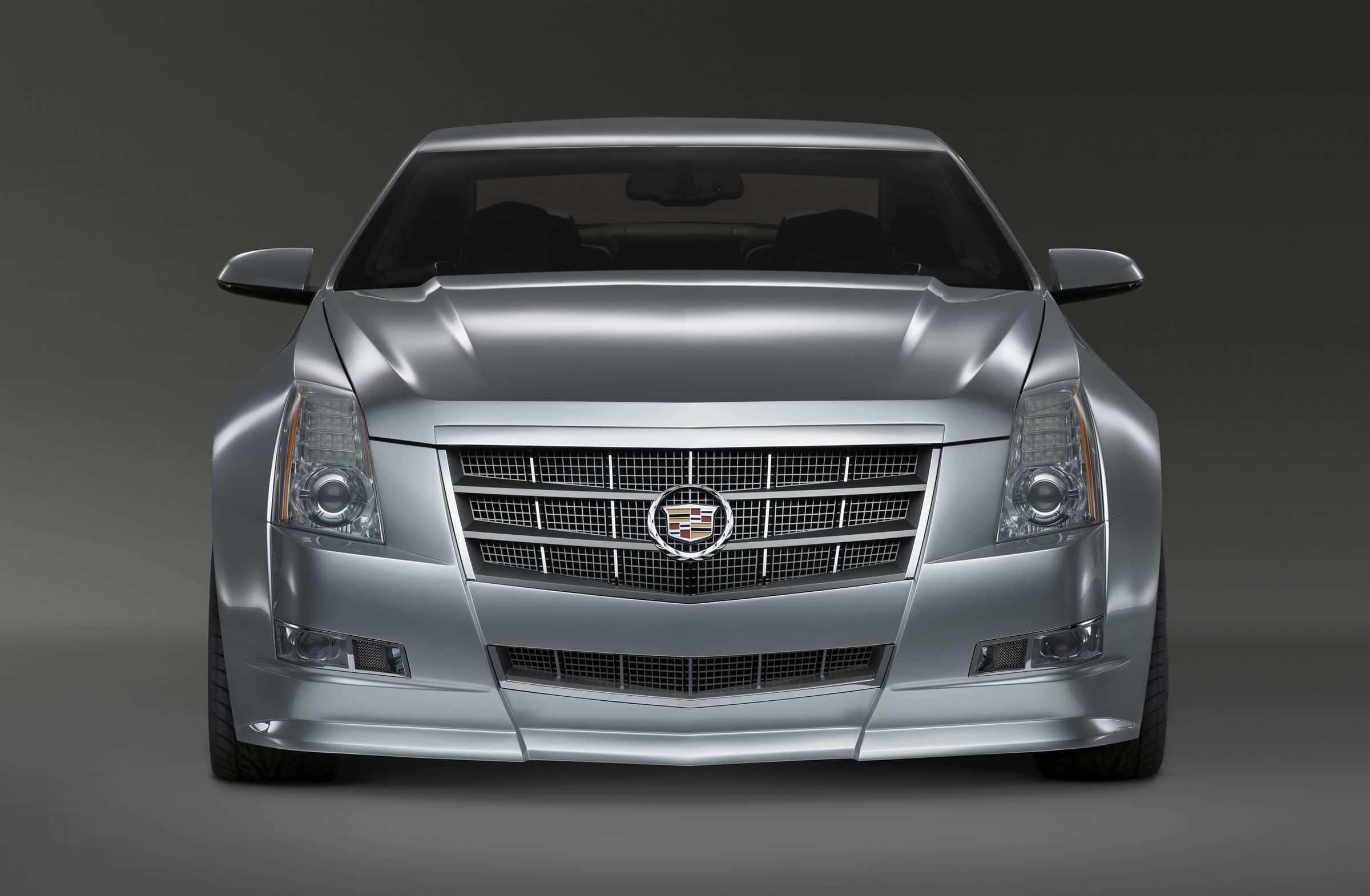 Cadillac Cts 桌布 壁紙 — 深灰色工作室背景前，一輛時尚銀色Cadillac ATS的正面視圖，配備鍍鉻格柵和鋒利頭燈。