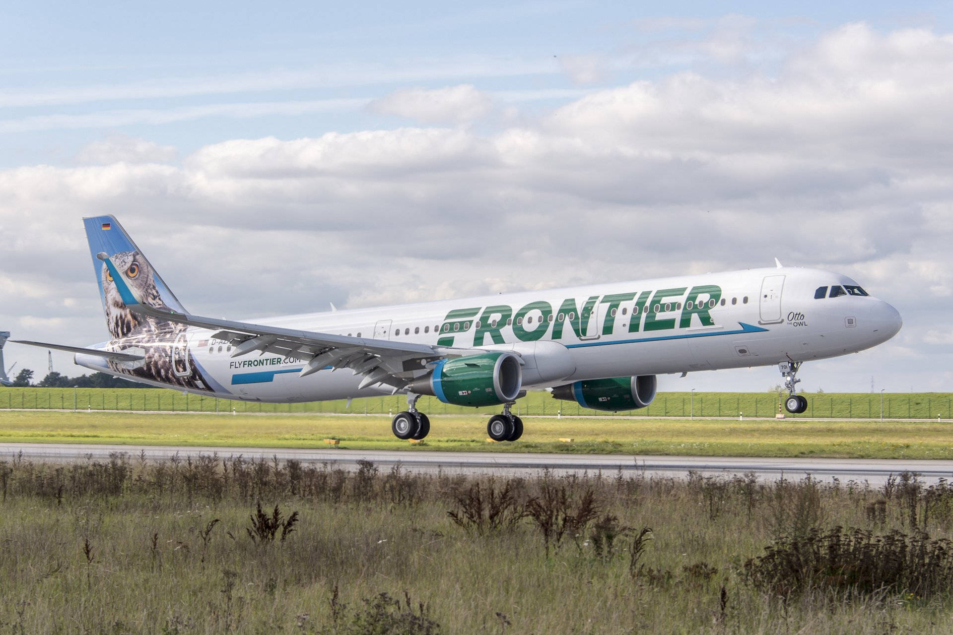 Frontier航空飛機準備起飛 壁紙 — 一架邊疆航空的空中巴士A321，帶有貓頭鷹塗裝，在部分多雲的天空下滑行在跑道上。