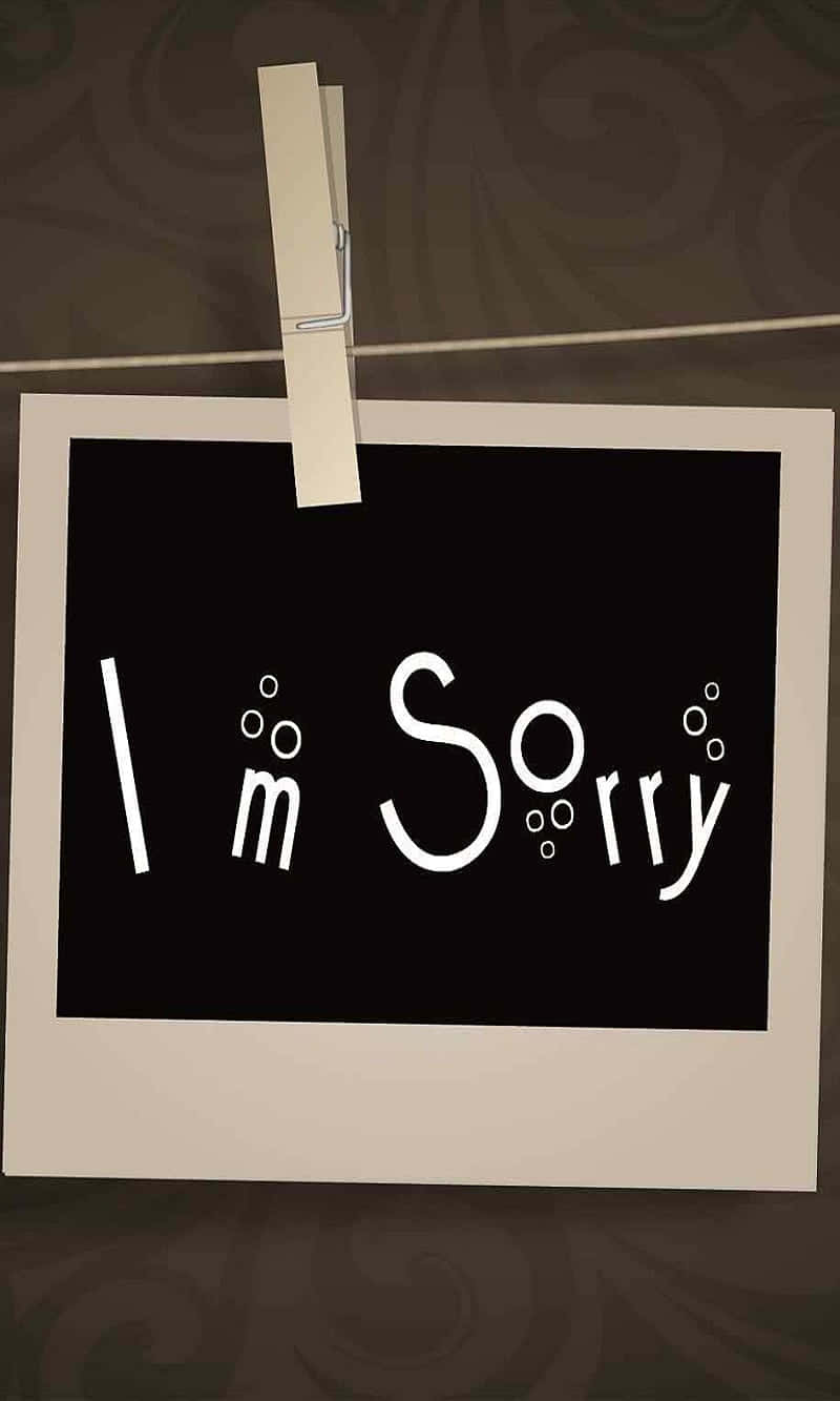  壁紙 — 一張復古照片印刷品，上面有氣泡白色字體的「I'm Sorry」，用衣夾夾在繩子上，背景是旋轉的棕色牆紙。
