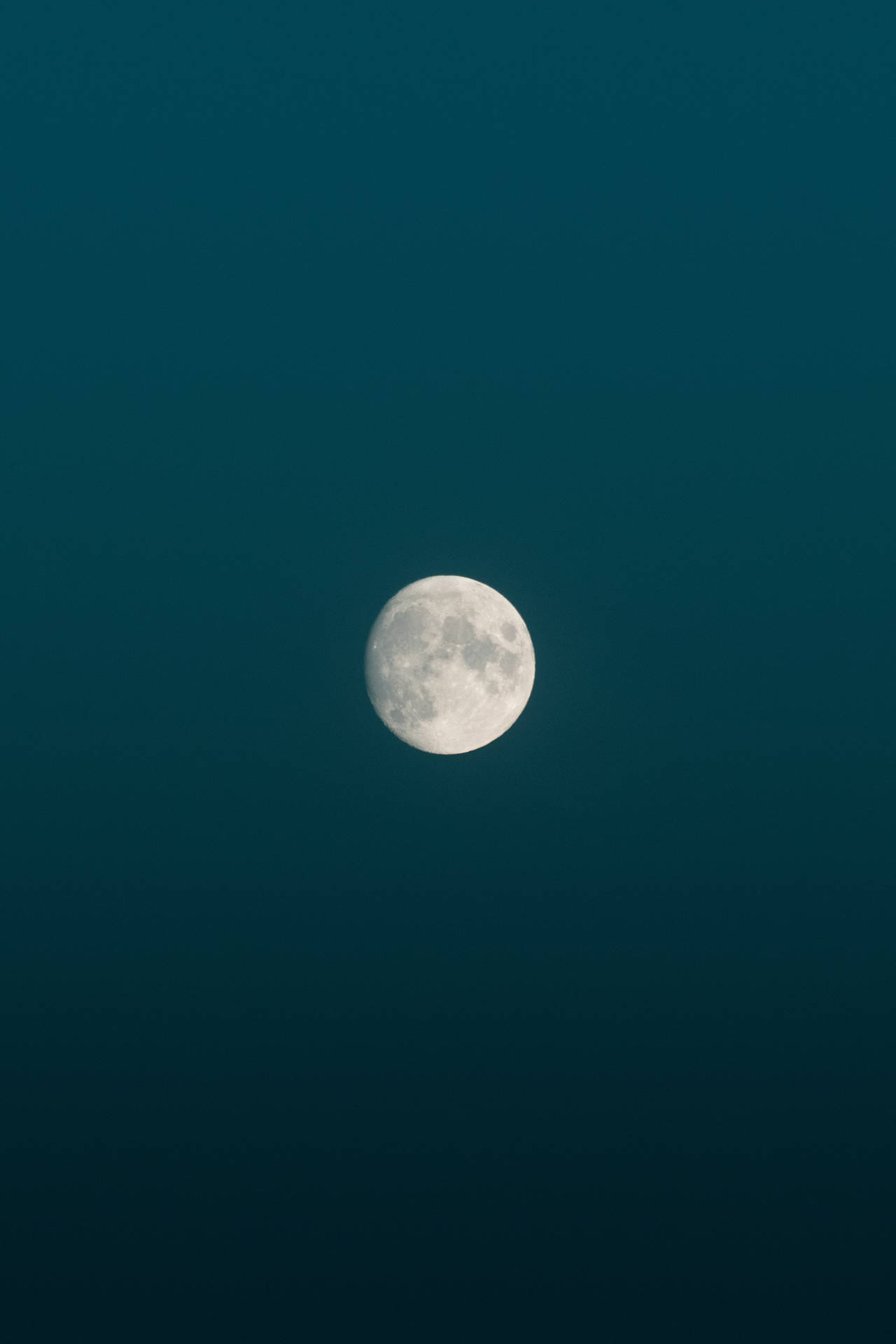 午夜時分，藍色極簡主義天空下，滿月輝耀其表面。