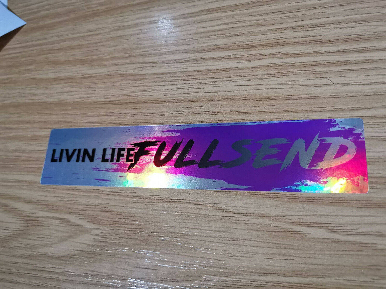 鐳射貼紙，上面寫著「LIVIN LIFE FULL SEND」，放在木頭上。