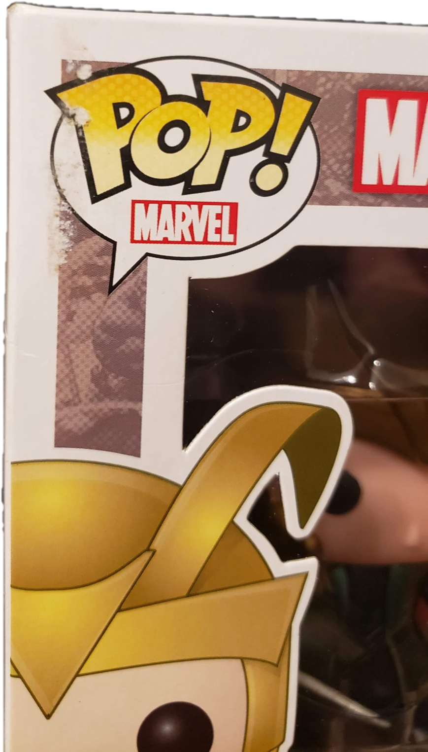 漫威洛基 Funko Pop! 包裝盒細節 壁紙 — 近距離拍攝的Funko Pop! Marvel人偶，金色頭盔和黑色眼睛透過包裝可見。
